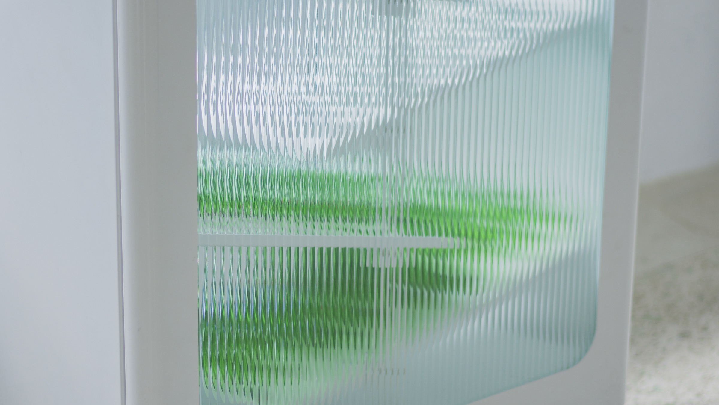 Green bottles refracted and multiplied through the fluted glass panel