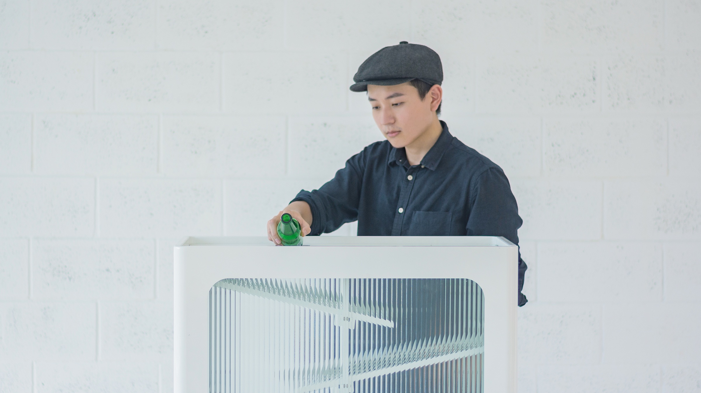 A designer inserting a glass bottle into the recycling bin