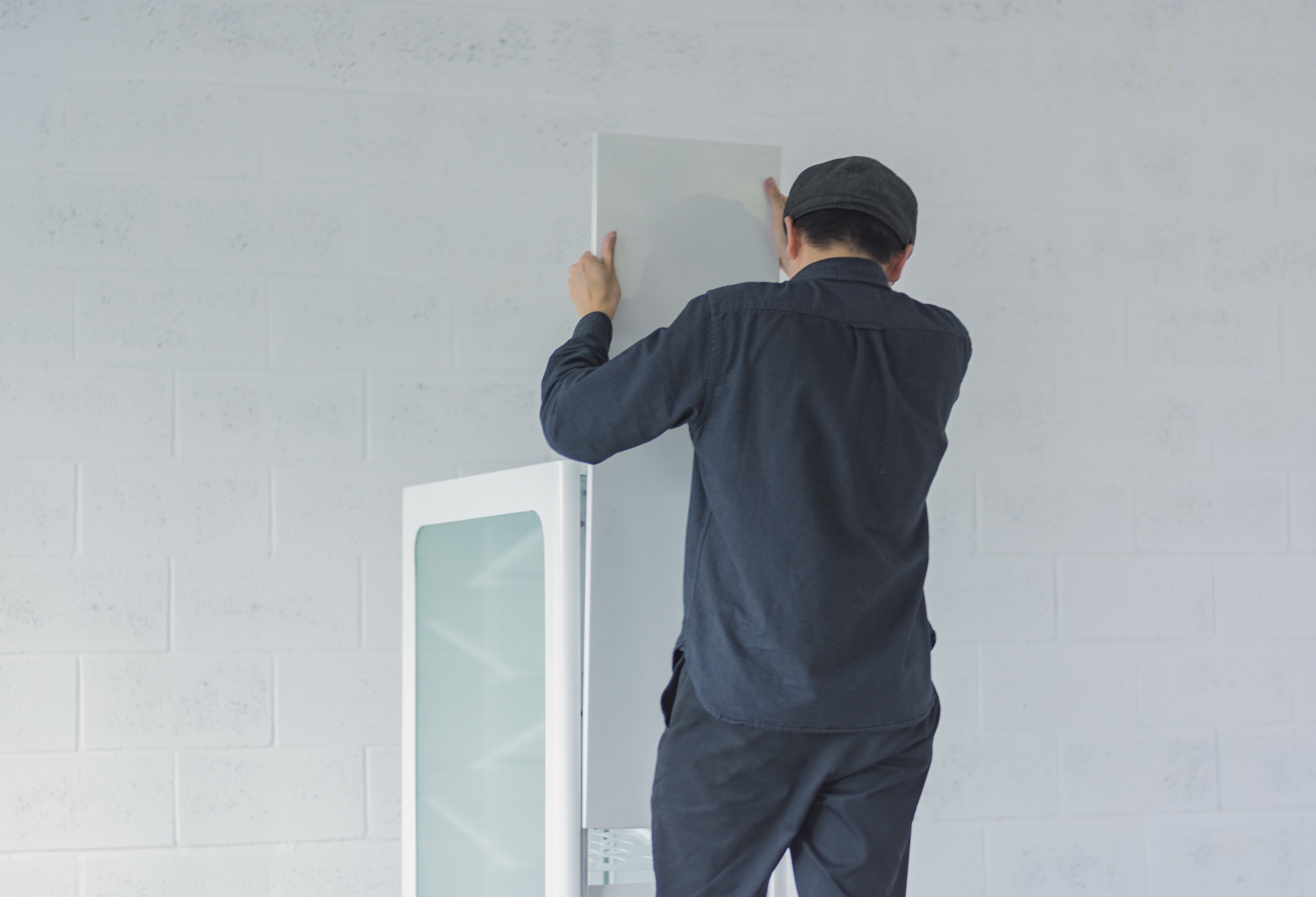 A designer fitting a fluted glass panel to the bin