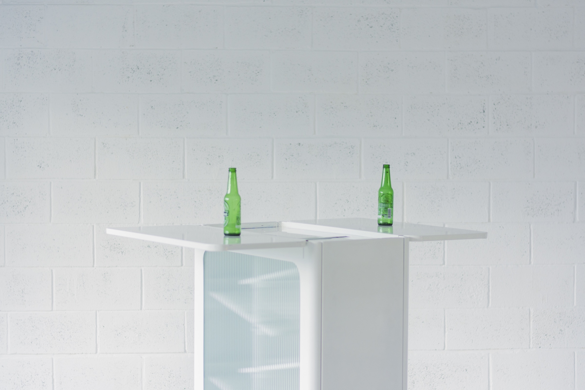The bar table with two bottles against a white wall