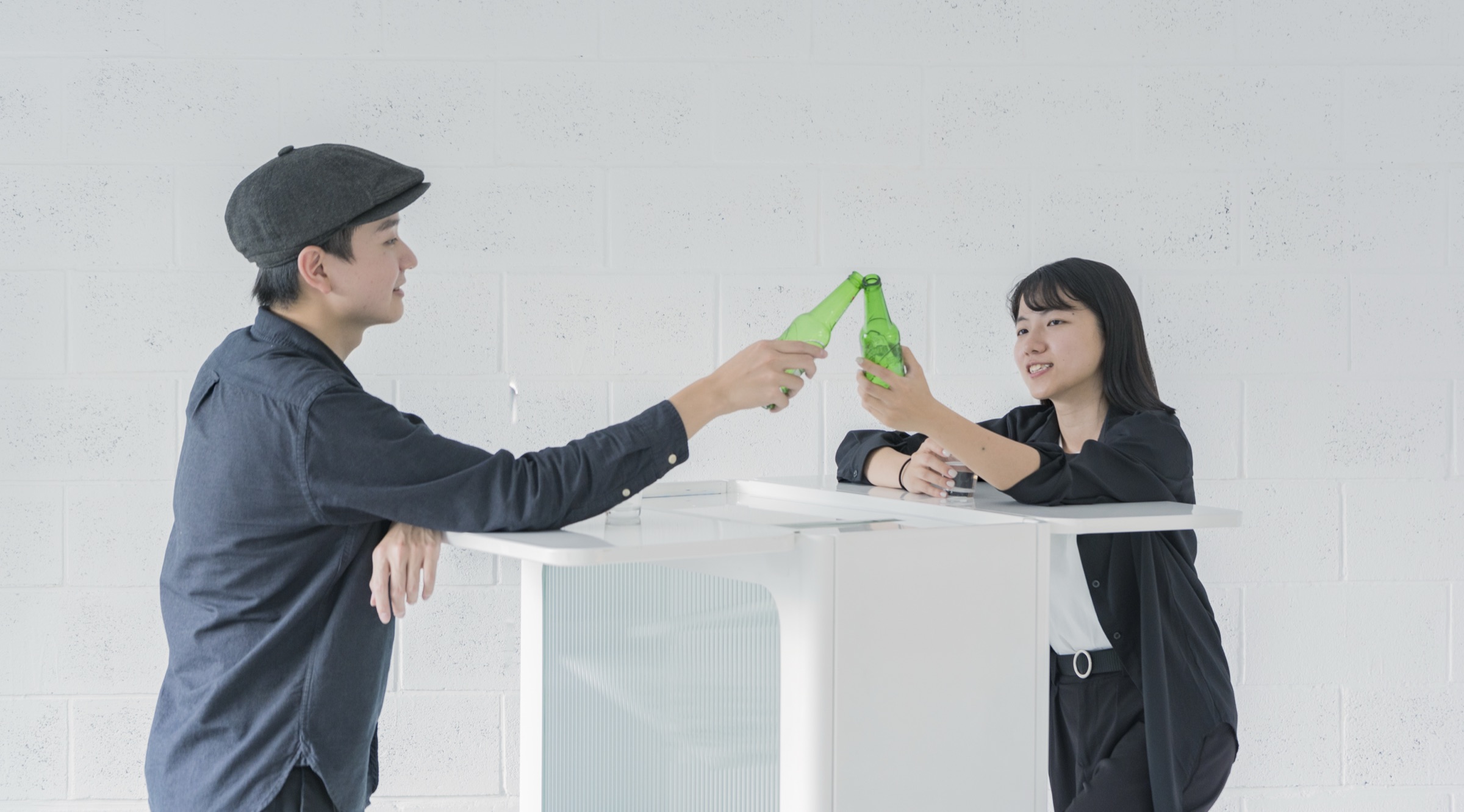 Two people toasting across the fluted-glass bar table