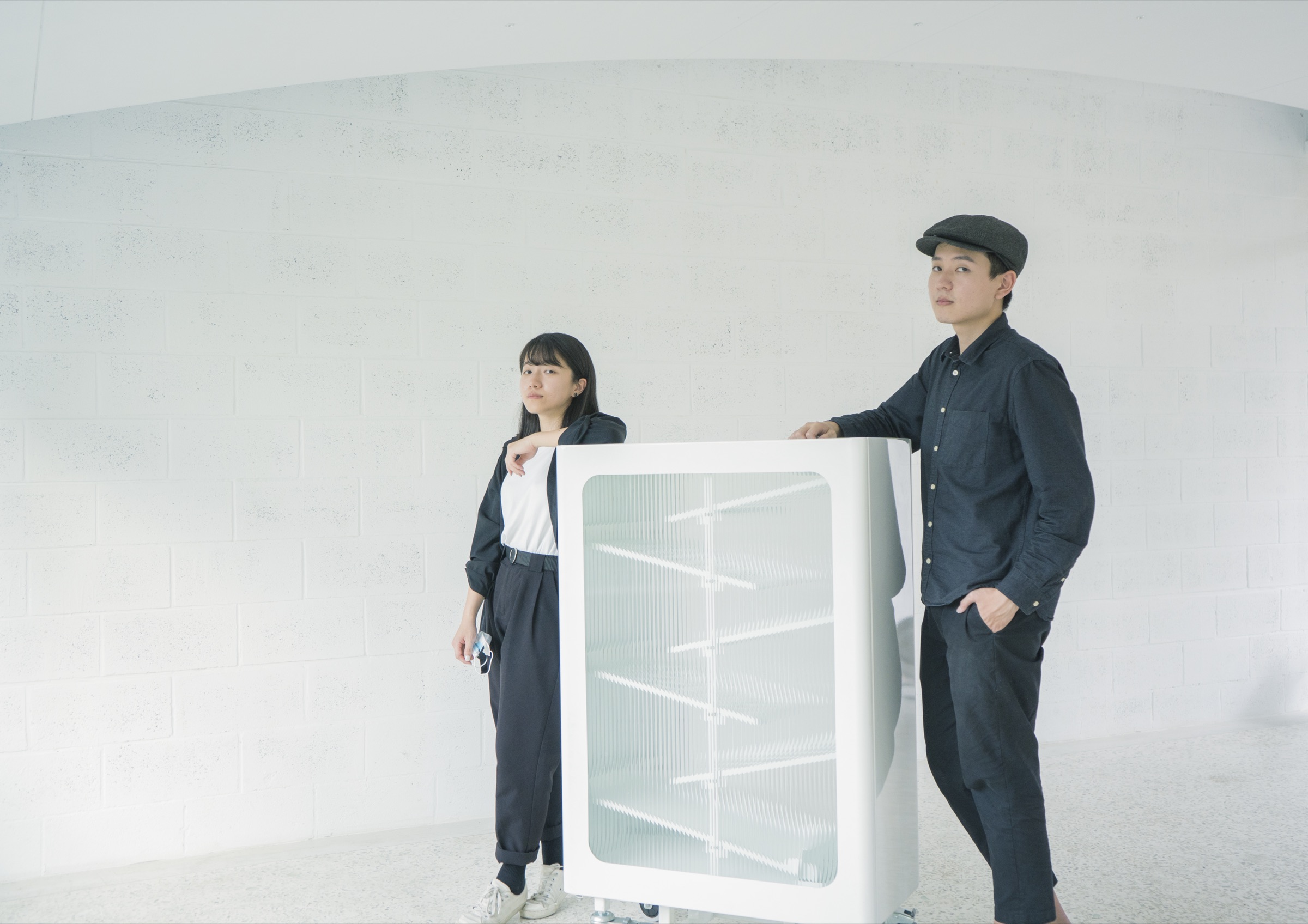 The two designers standing beside the finished recycling bin