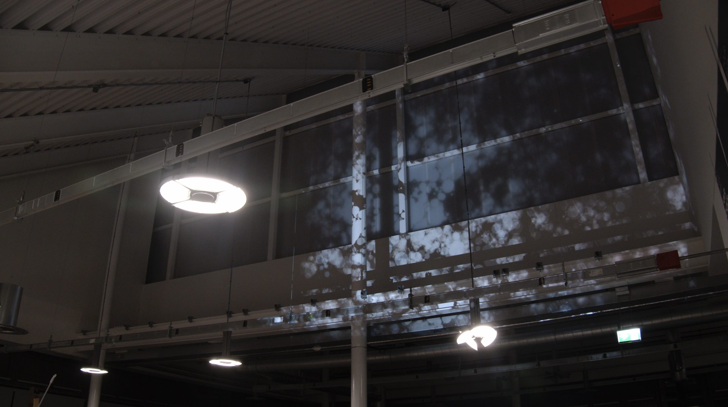 The Raindrops projection across suspended panels in an industrial space