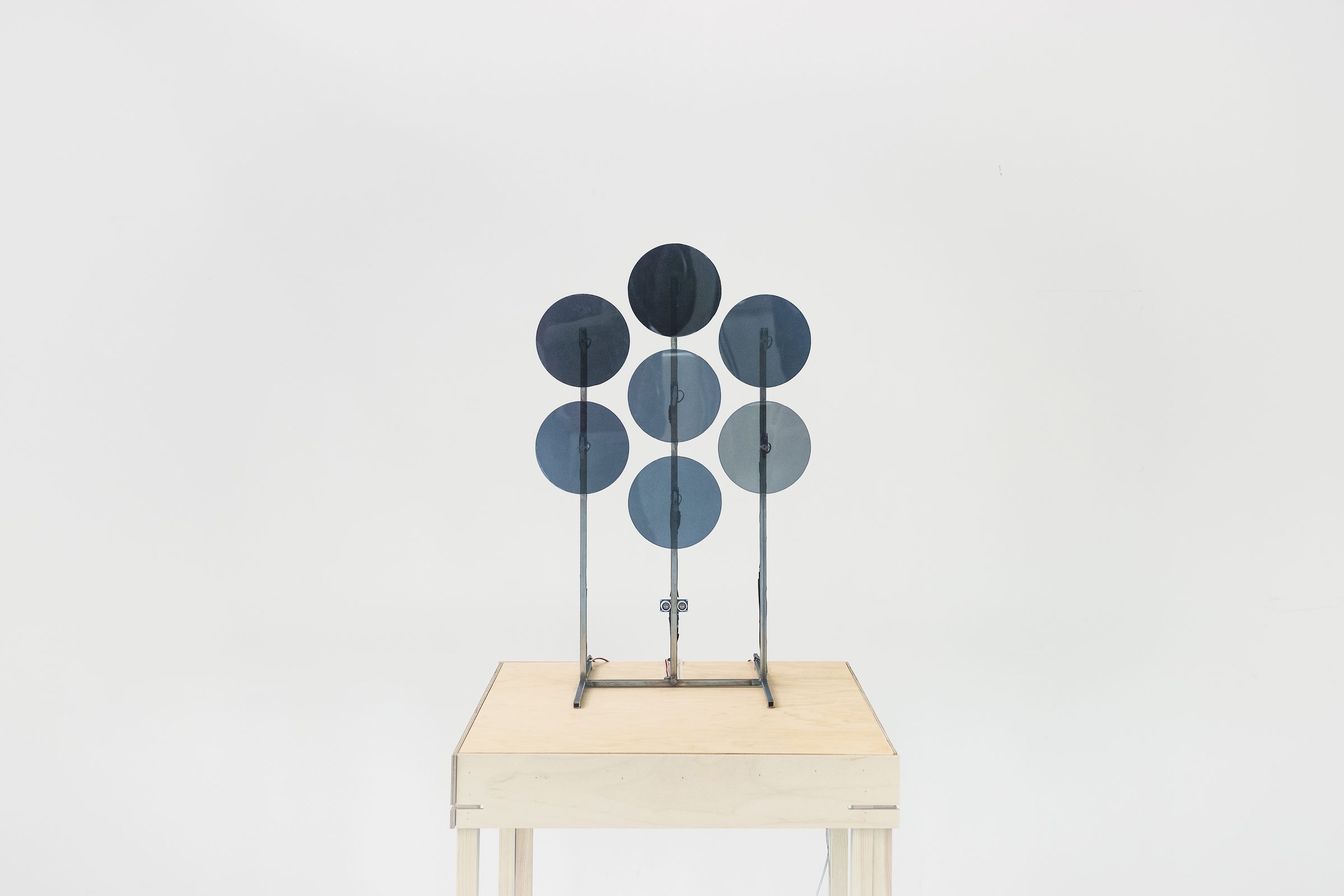Seven polarised circular panels arranged in a hexagonal grid on a plinth