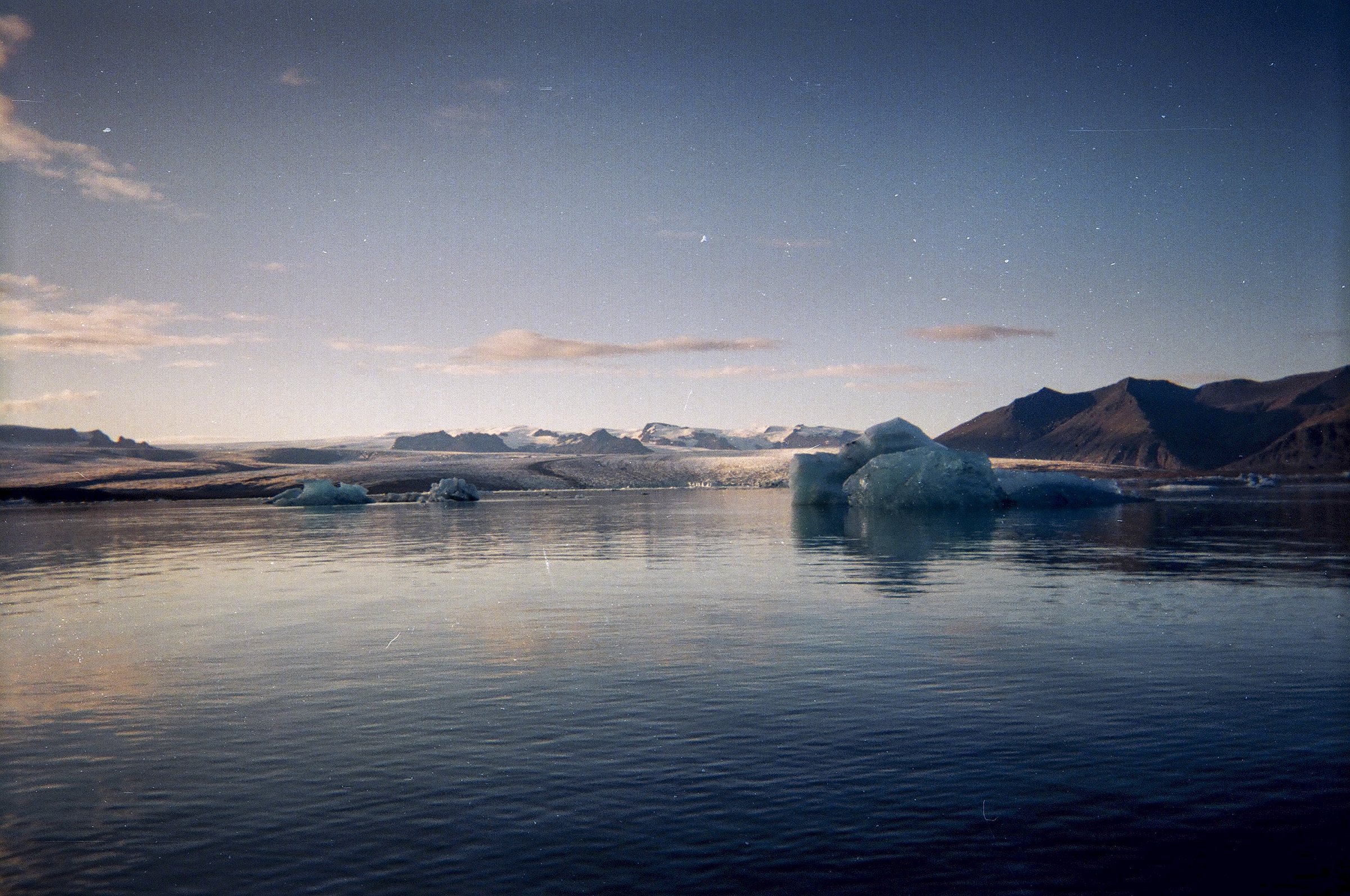 A glacial lagoon in Iceland at dusk with icebergs on still water
