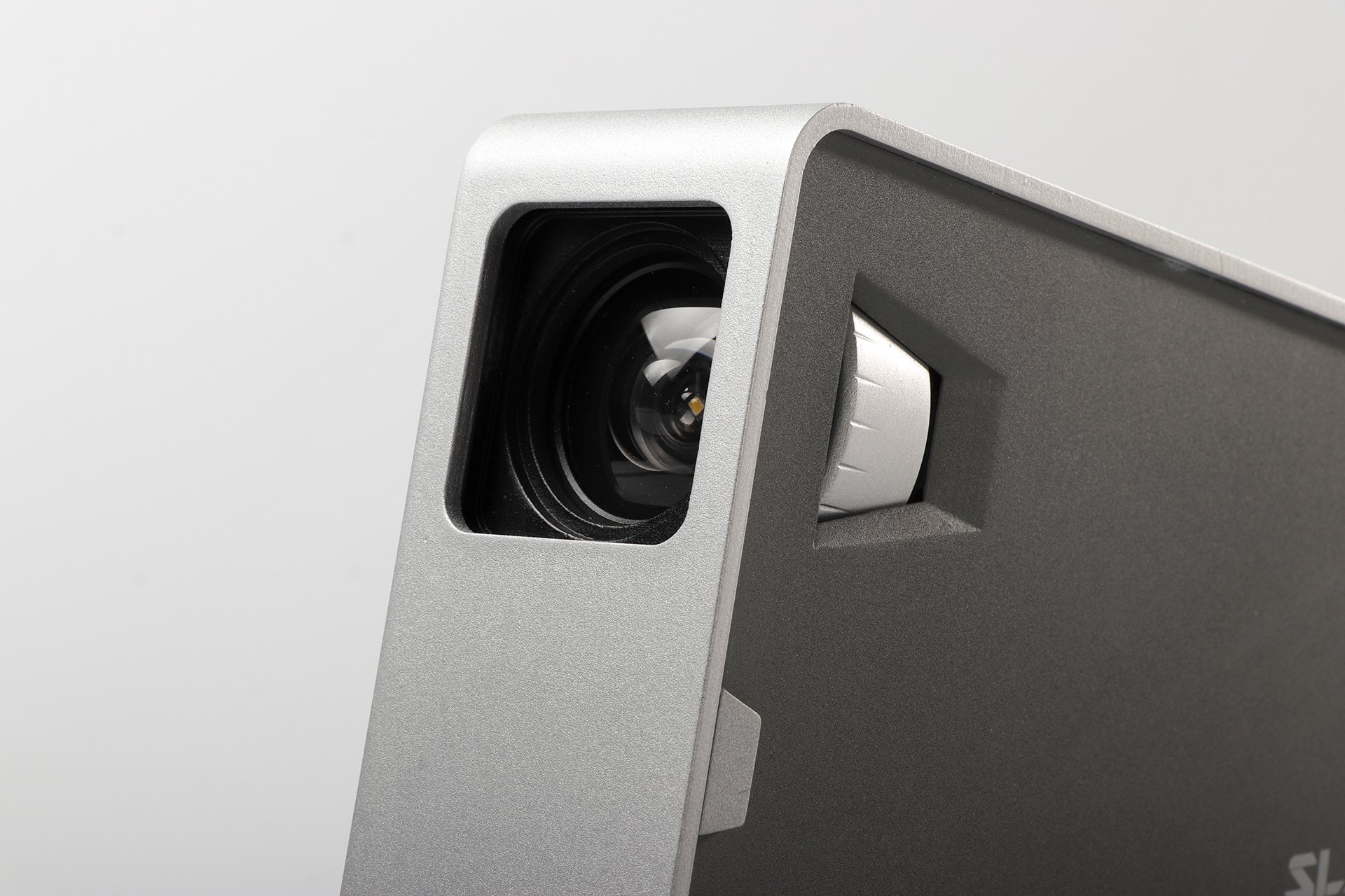 Close-up of the SLANT projector's lens and focus dial in machined aluminium