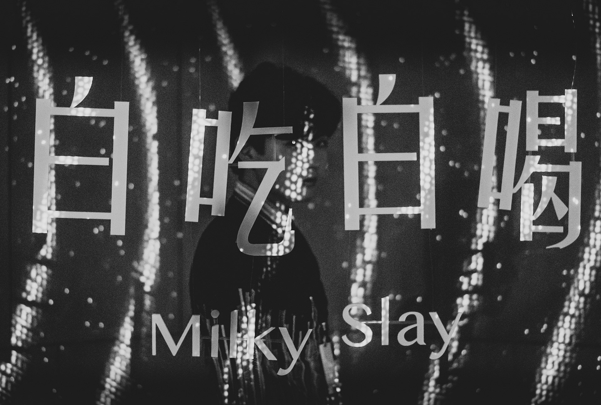 The Milky Slay exhibition title projected in light across a figure in a dark space