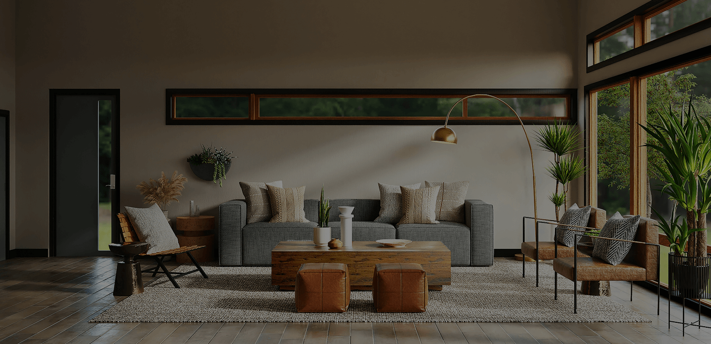 Modern living room with a gray sofa, wooden coffee table, brown leather poufs, armchairs with patterned cushions, and large windows showing greenery outside.