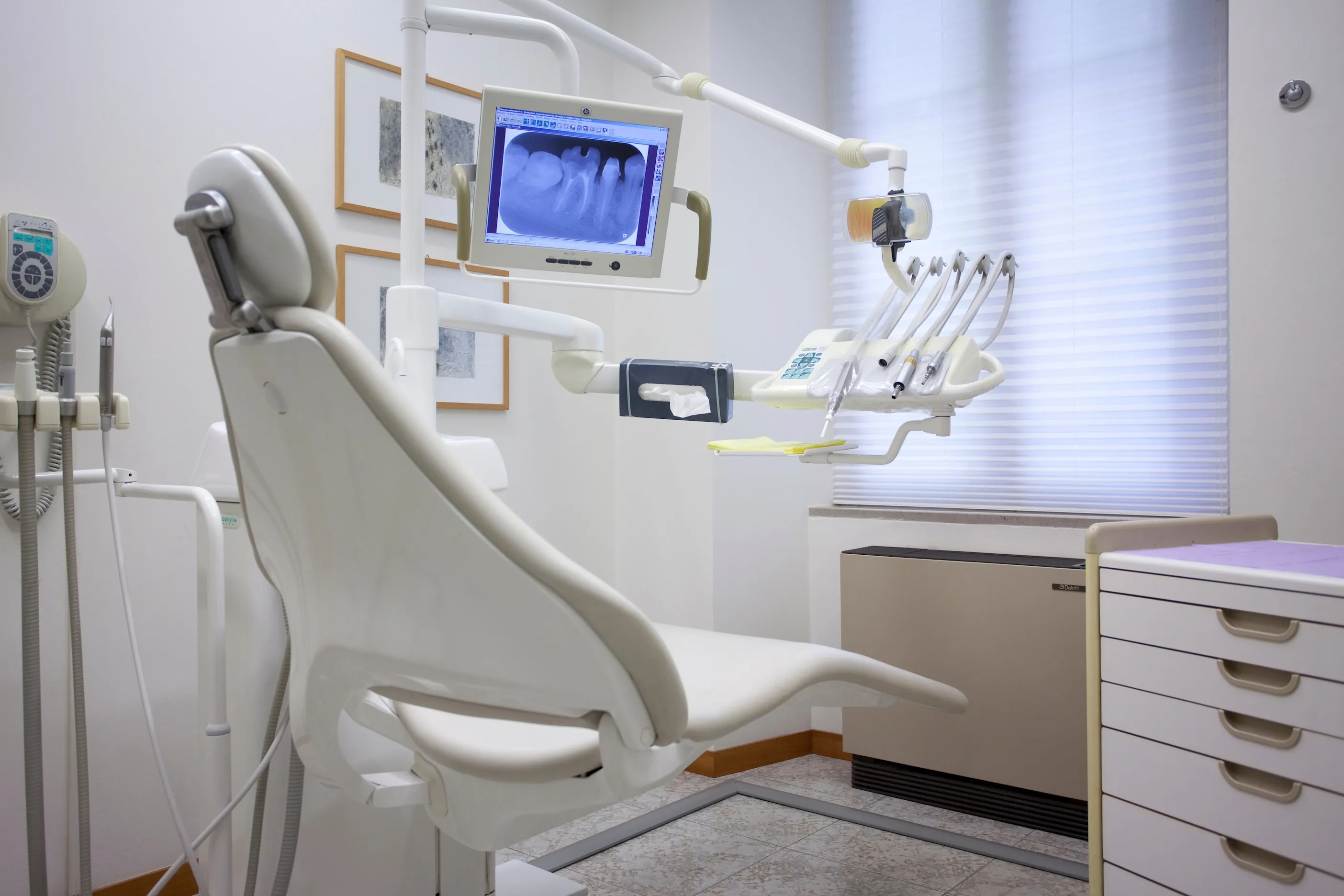 Modern dental treatment room with a chair and a digital dental X-ray on the monitor