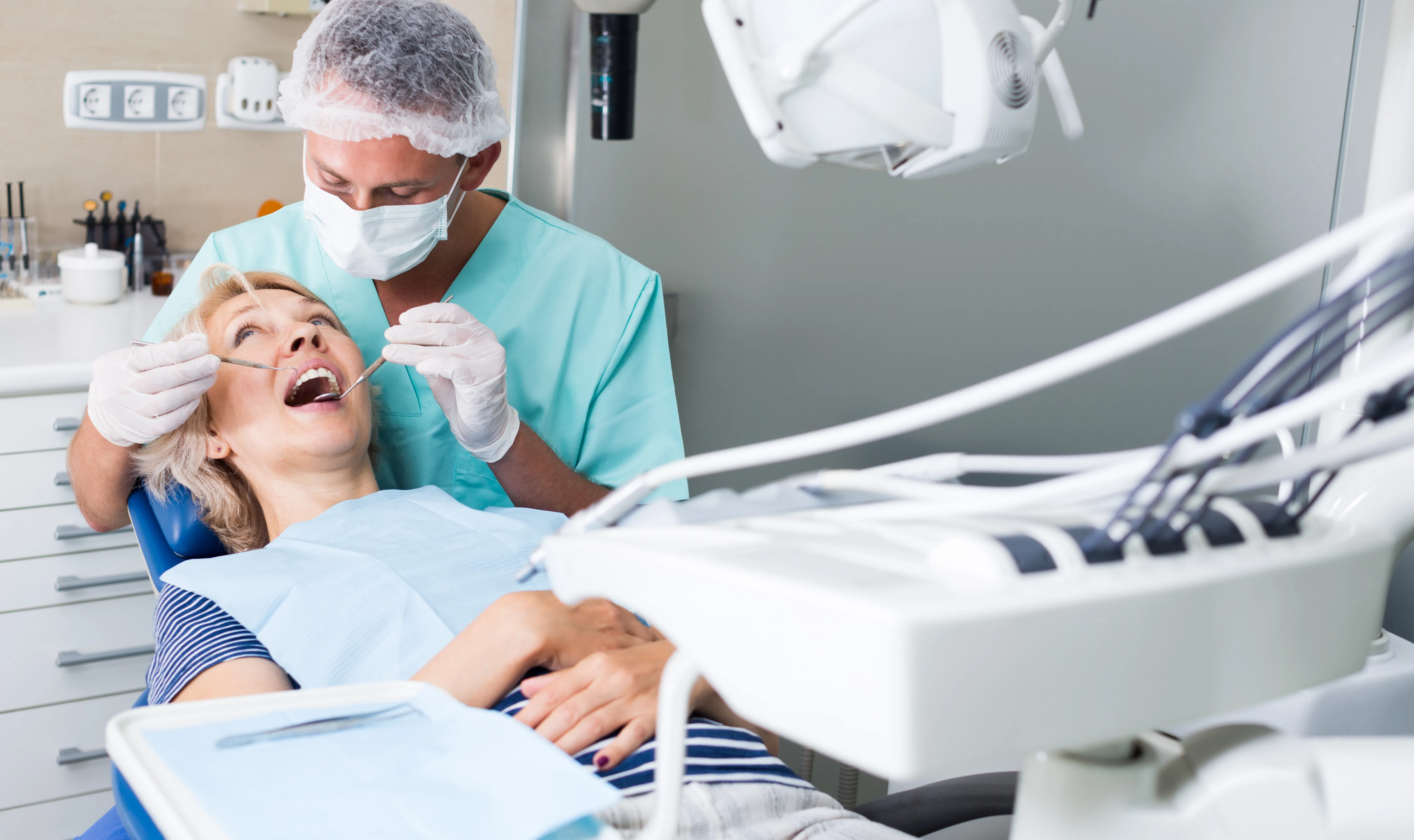 A dentist examining an older patient's teeth in the dental chair