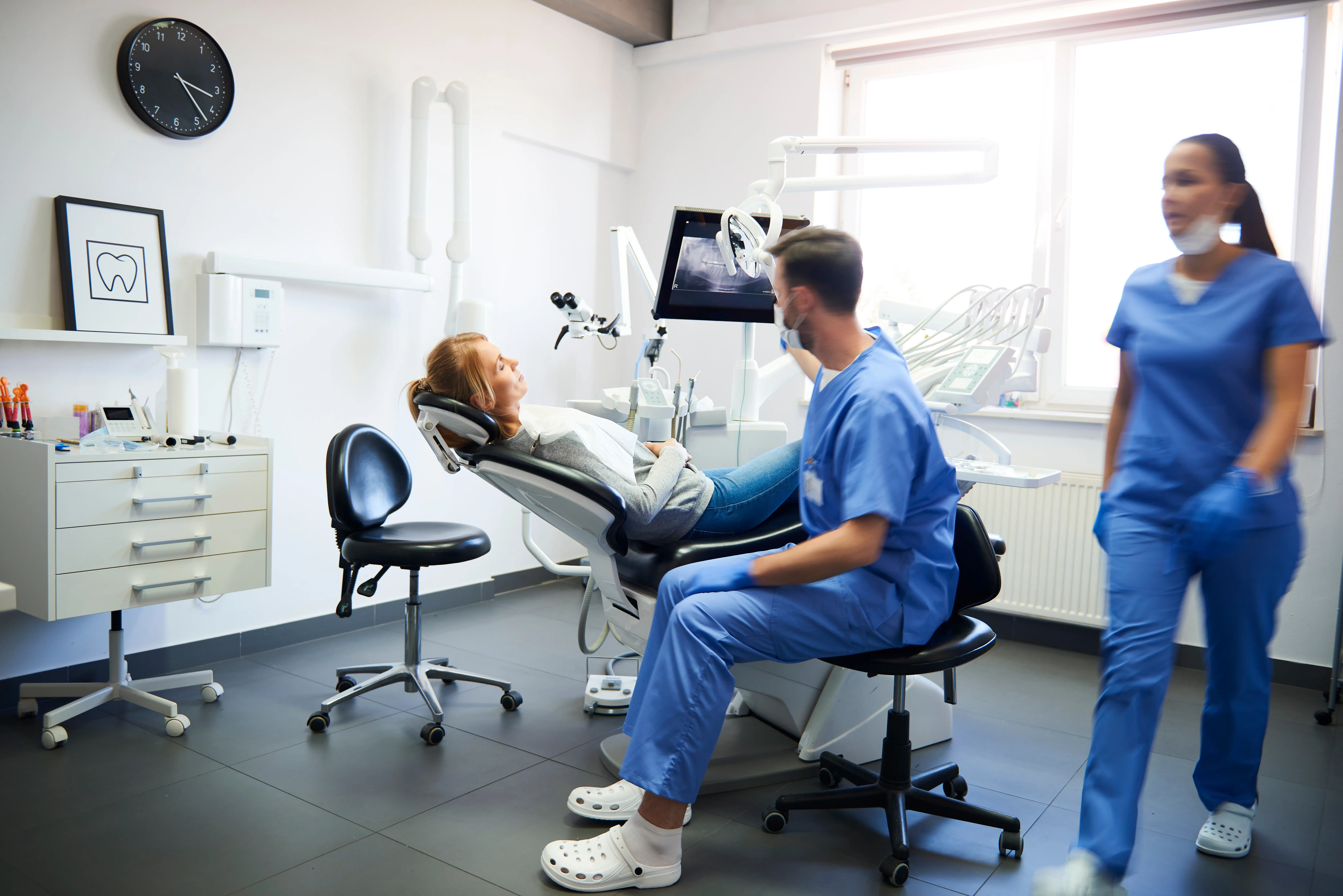 Dental team caring for a reclined patient in a modern treatment room