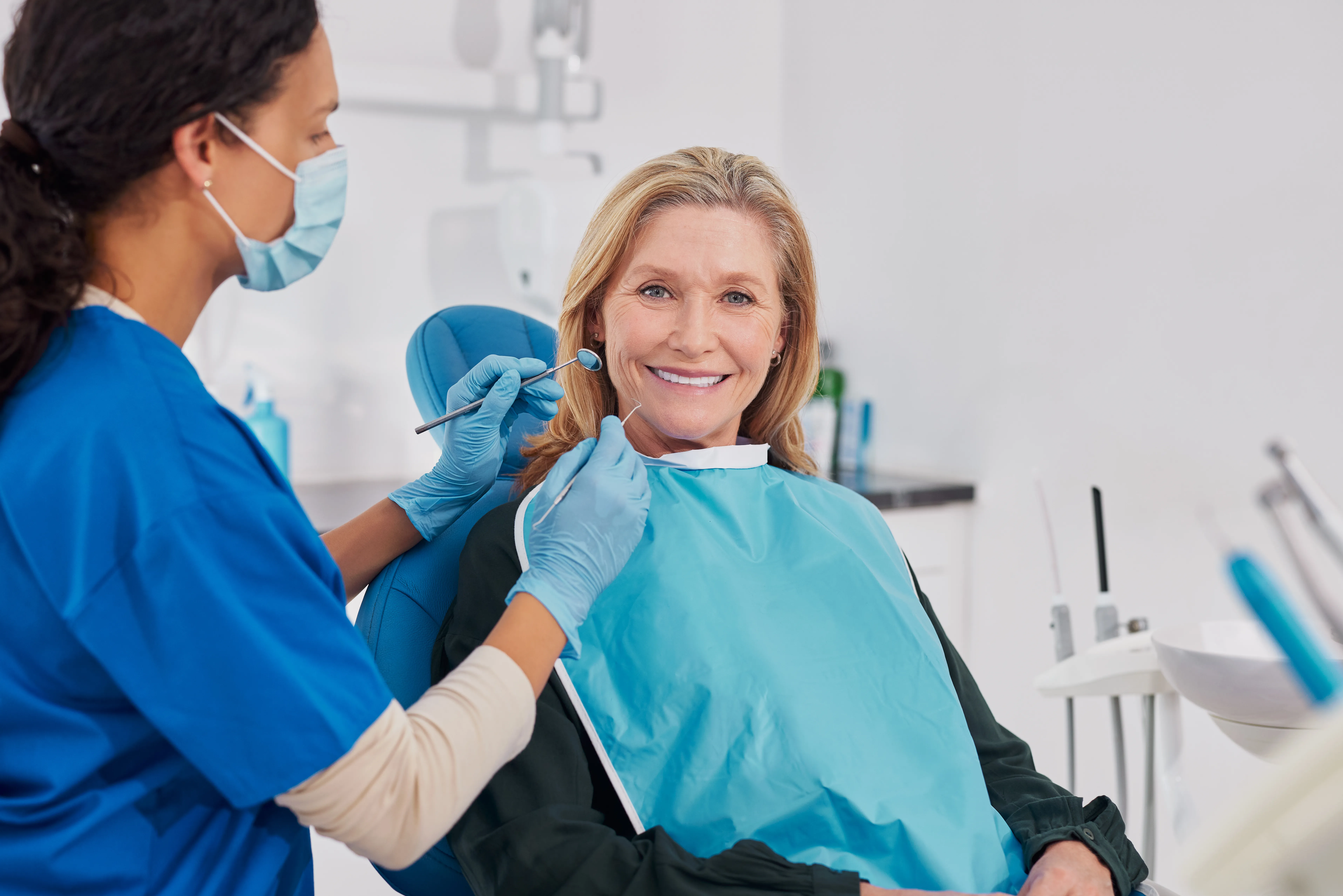 Dental hygienist treating a smiling older woman during a dental visit