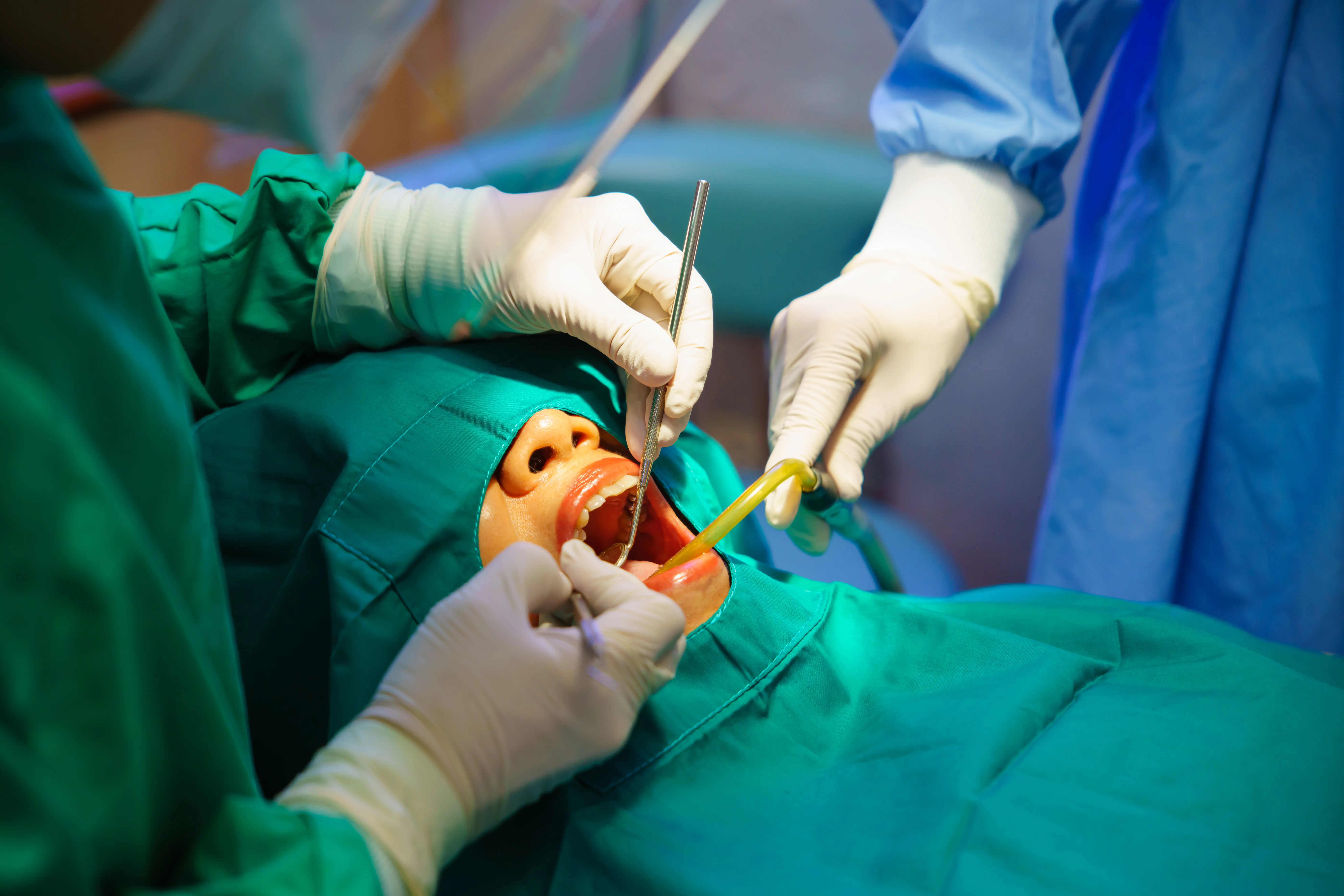 Oral surgery in progress on a draped patient, with instruments in the mouth