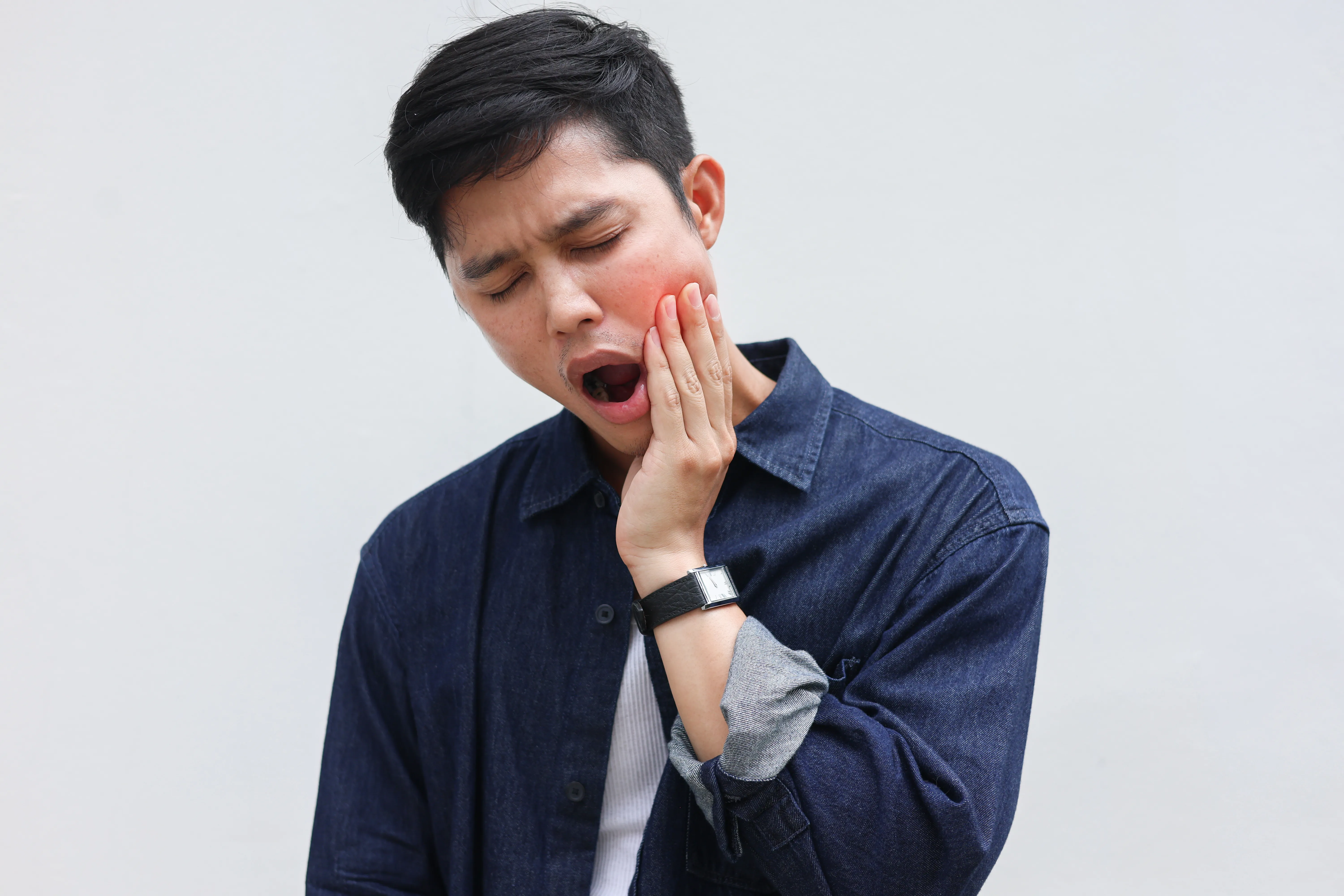 Young man suffering from painful jaw joints