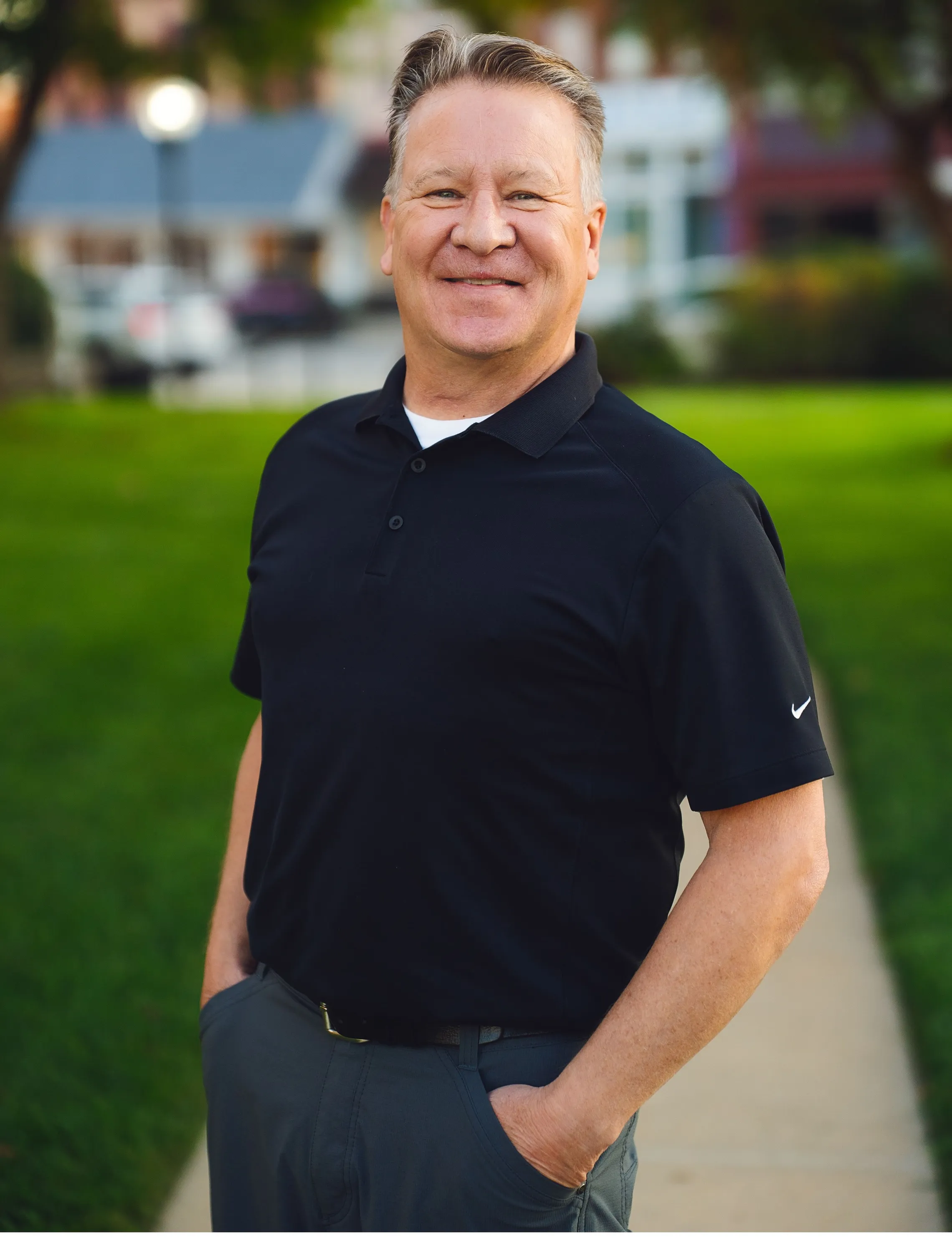 Portrait of Dr. Phillip Markham standing outdoors on a tree-lined sidewalk in Harlan