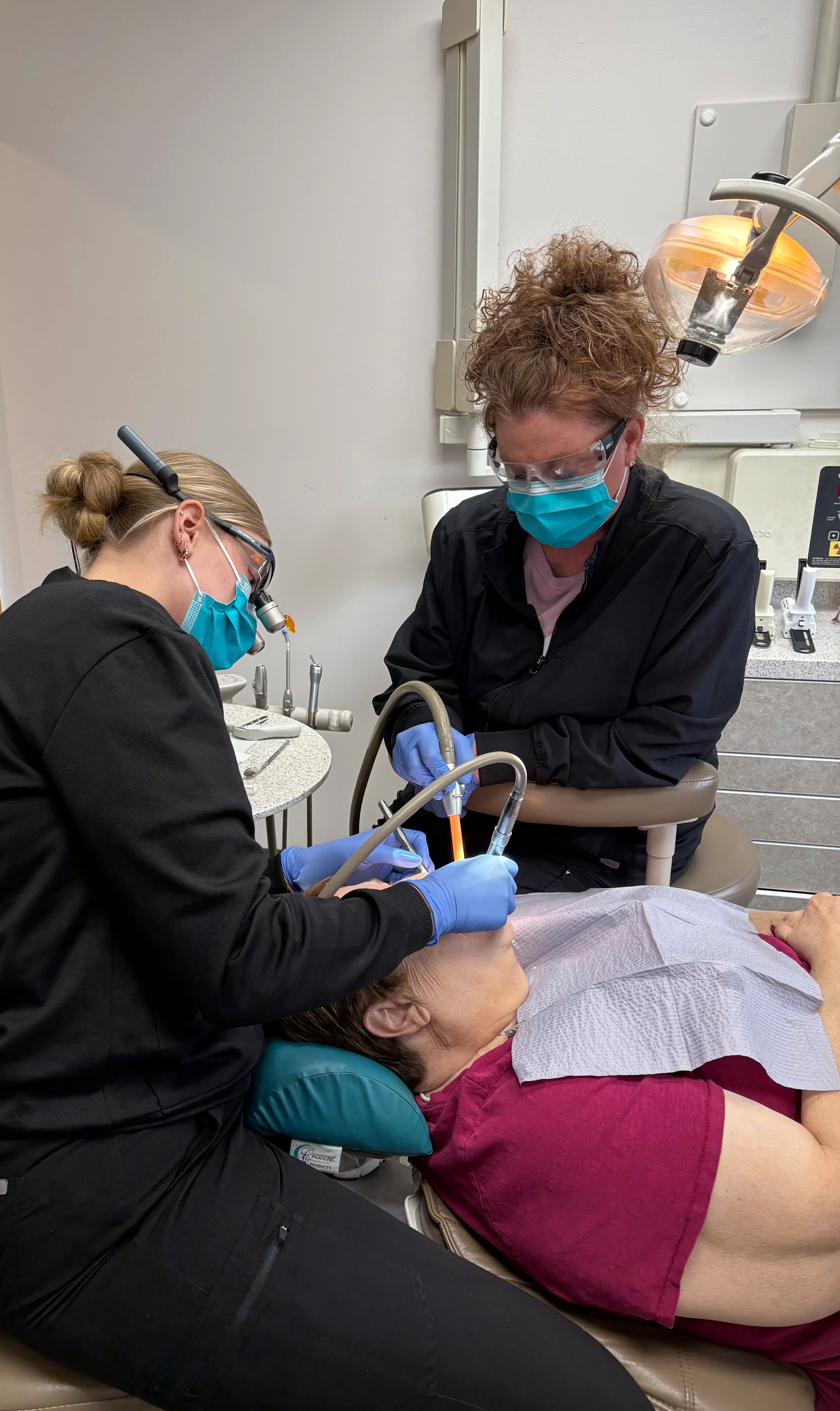 Two dental hygienists cleaning a patient's teeth at Markham Family Dental