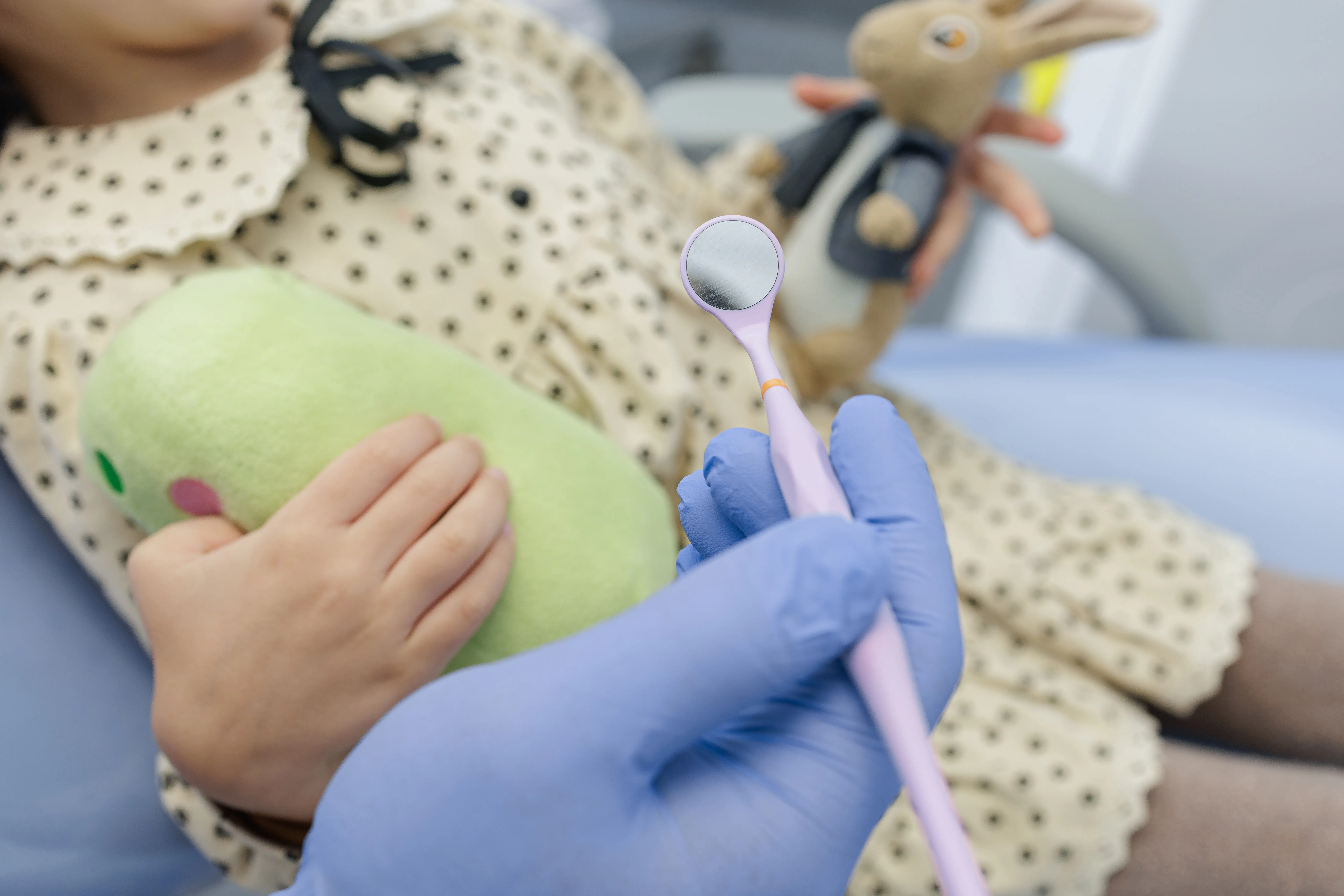Young child holding a plush toy during a gentle dental visit
