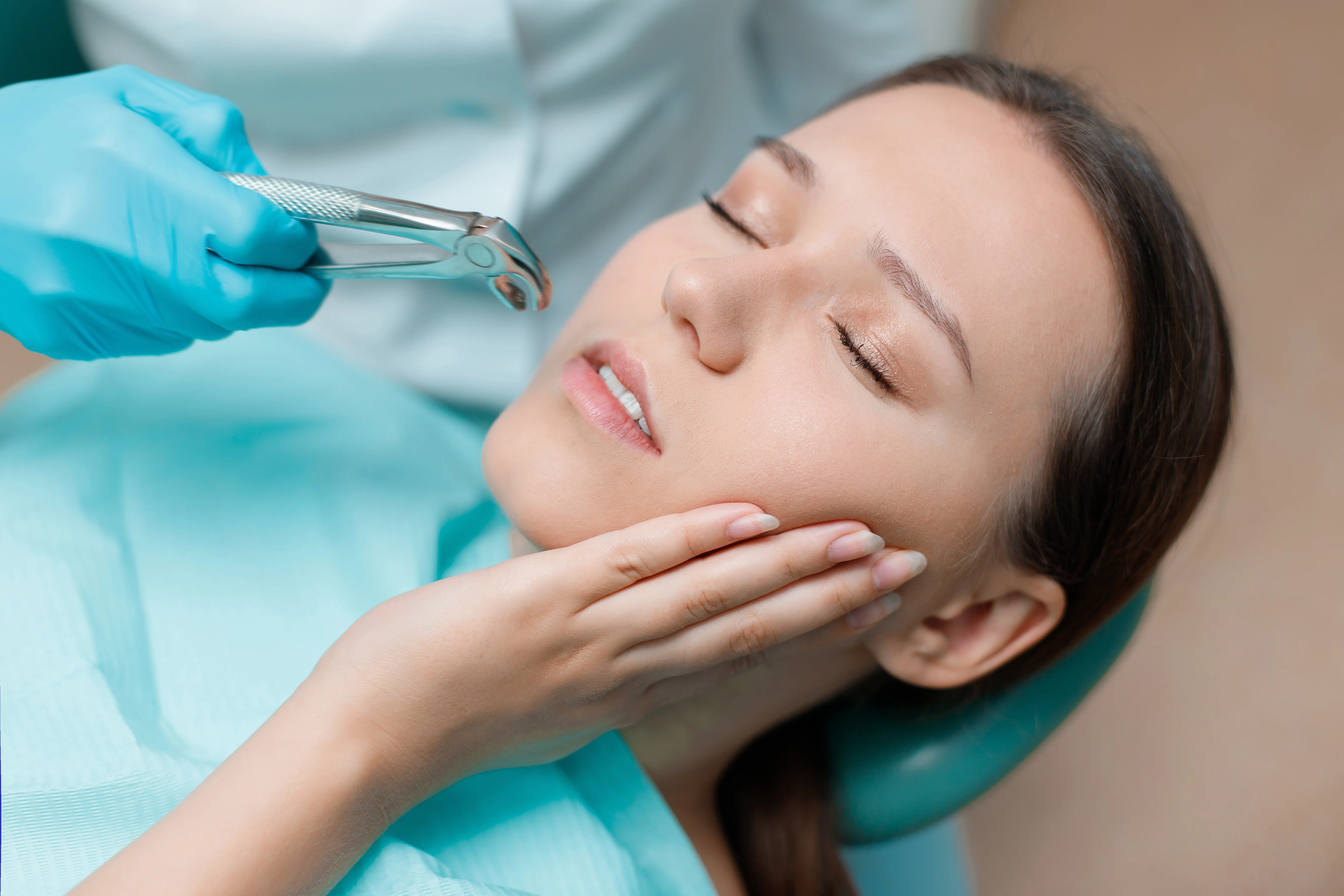 Young woman in a dental chair as a dentist uses forceps to remove a back tooth