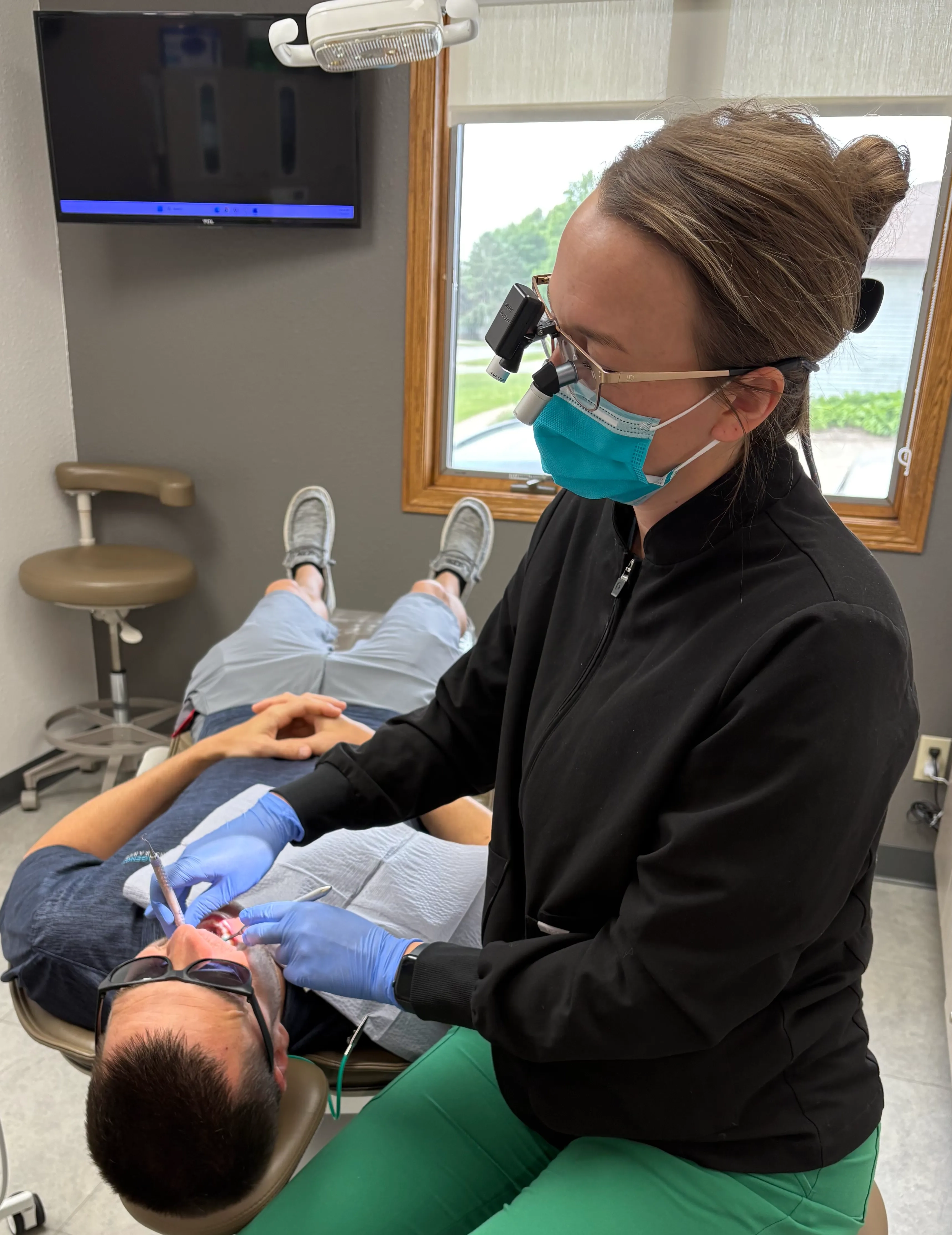 Dental team member examining a patient's open mouth with a mirror during a checkup