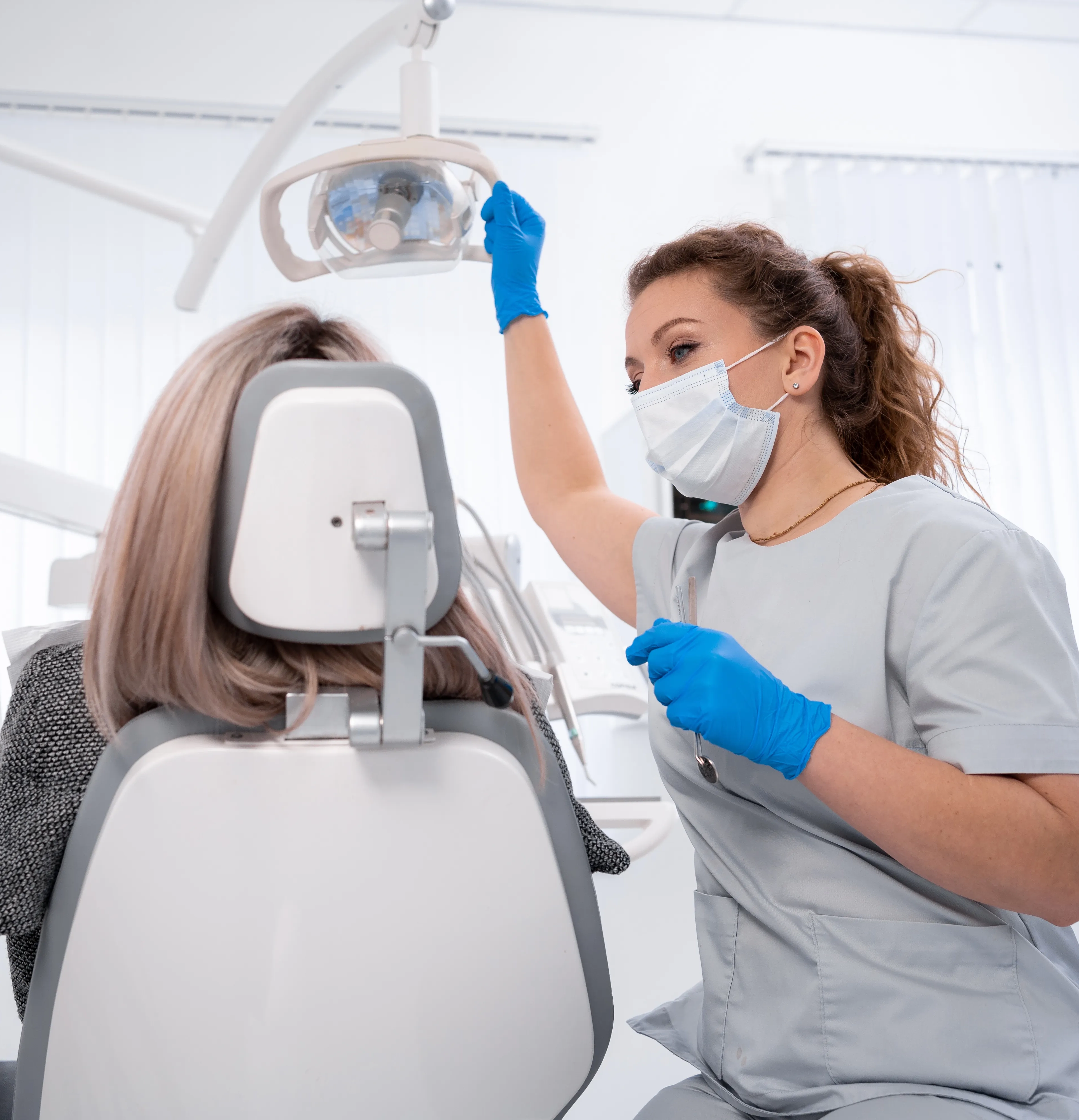 Dentist adjusting the overhead light beside a dental chair in a modern operatory