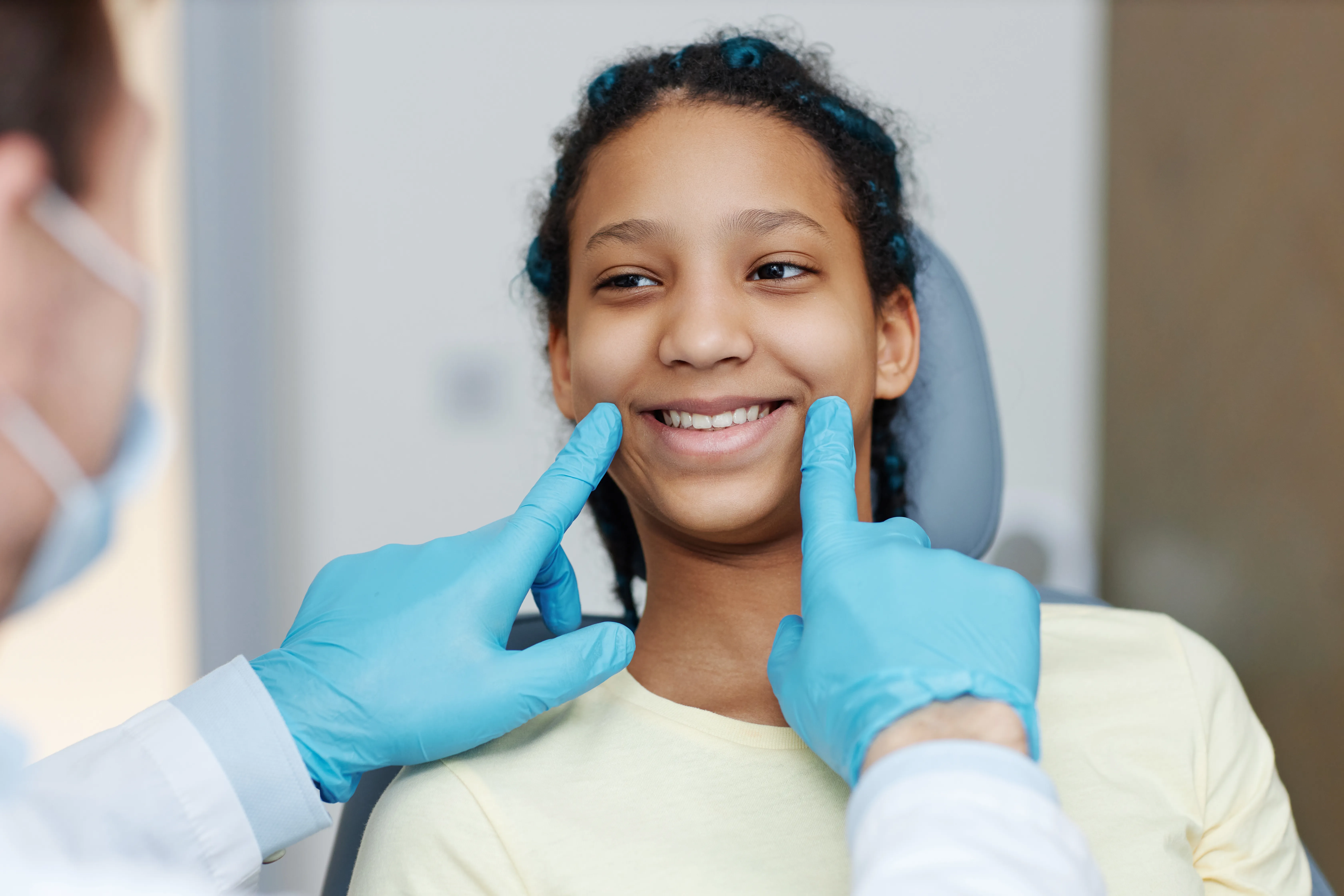 Smiling patient having her teeth evaluated before cosmetic whitening treatment