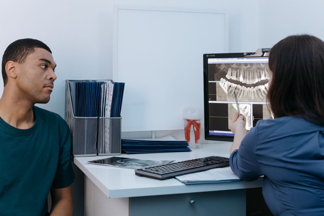 Dentist reviewing a dental X-ray with a patient during an urgent-care consultation