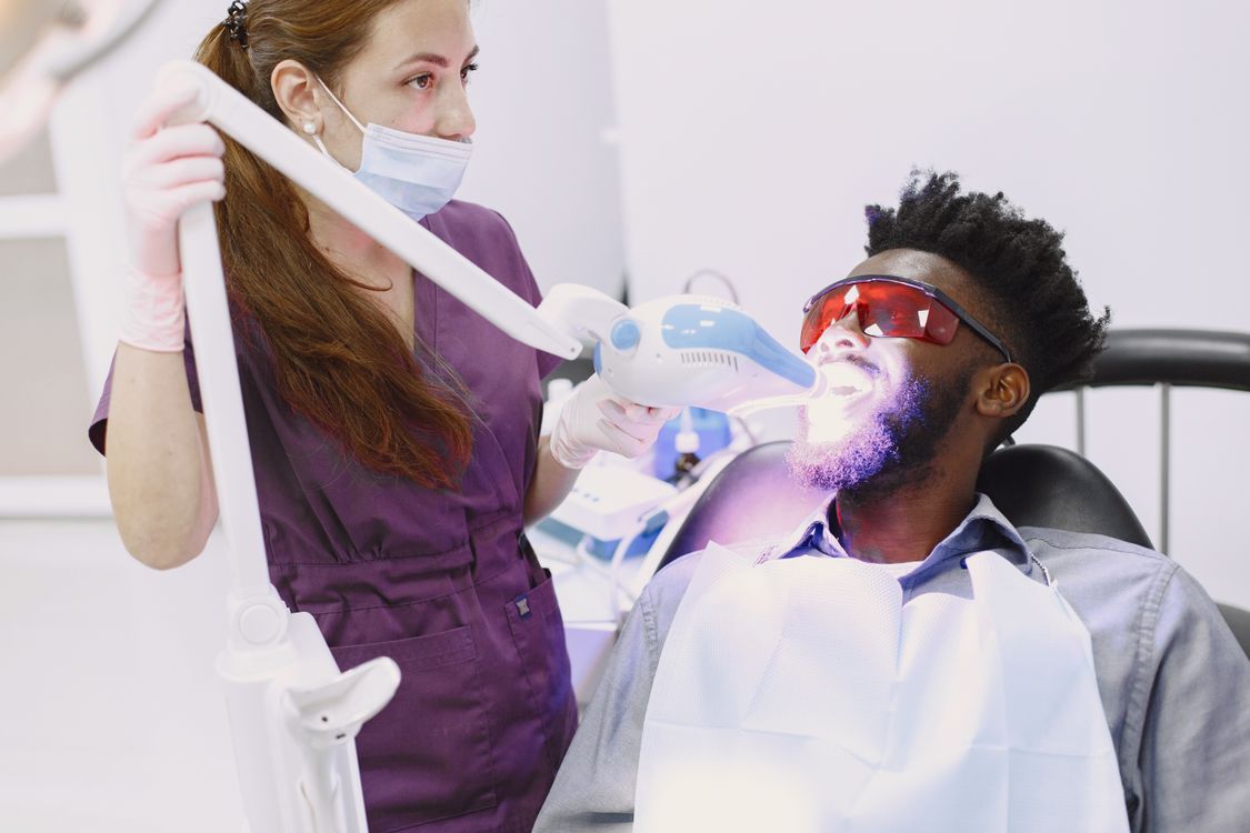 Dentist performing a supervised teeth whitening procedure on a patient