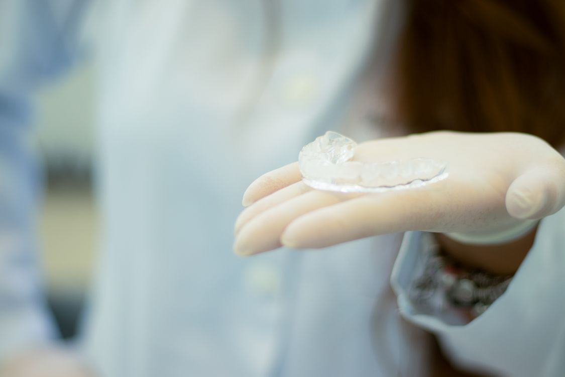 Dental professional holding a transparent mouthguard used to protect teeth from grinding
