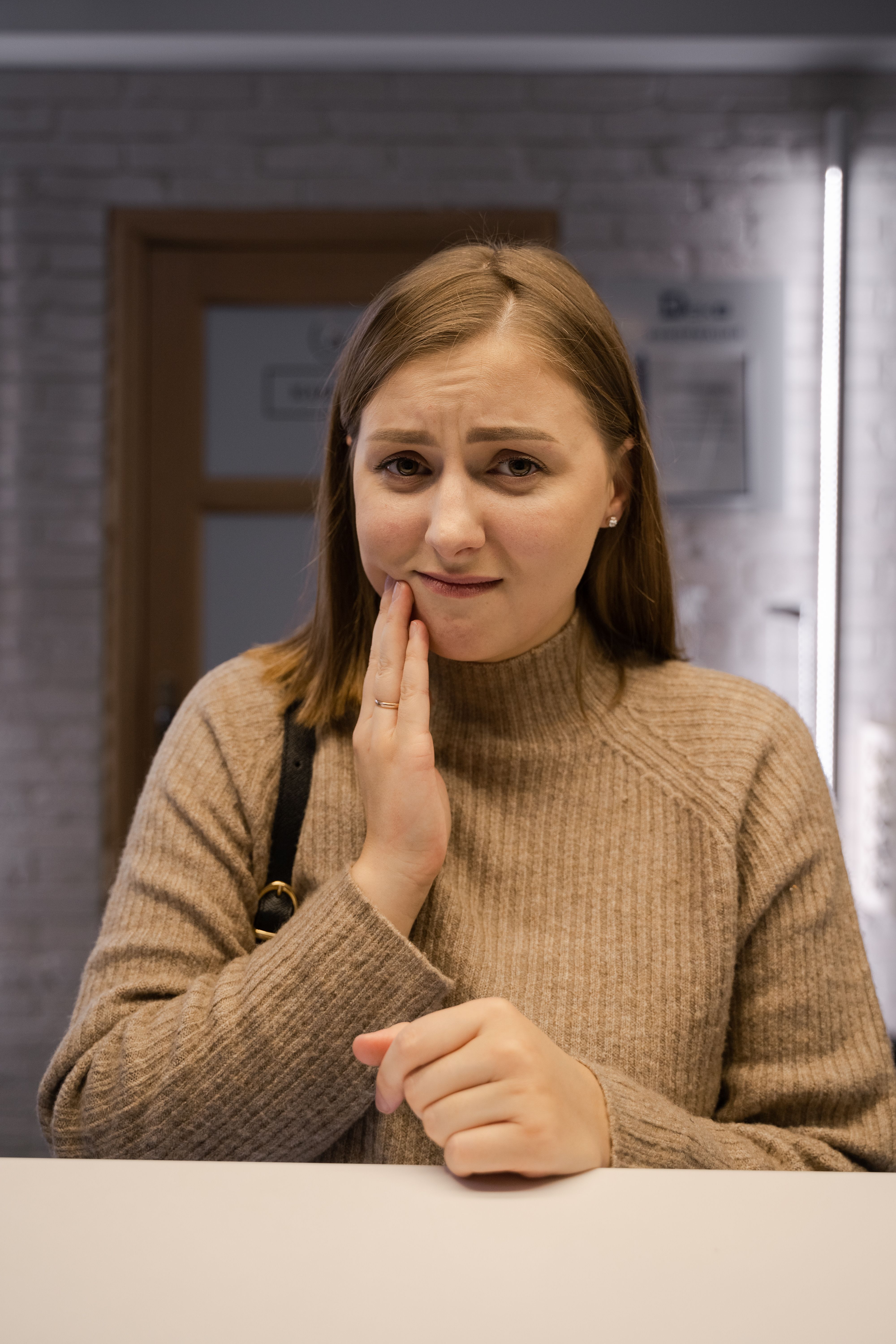 Patient in a dental clinic holding her jaw in discomfort from sudden tooth pain