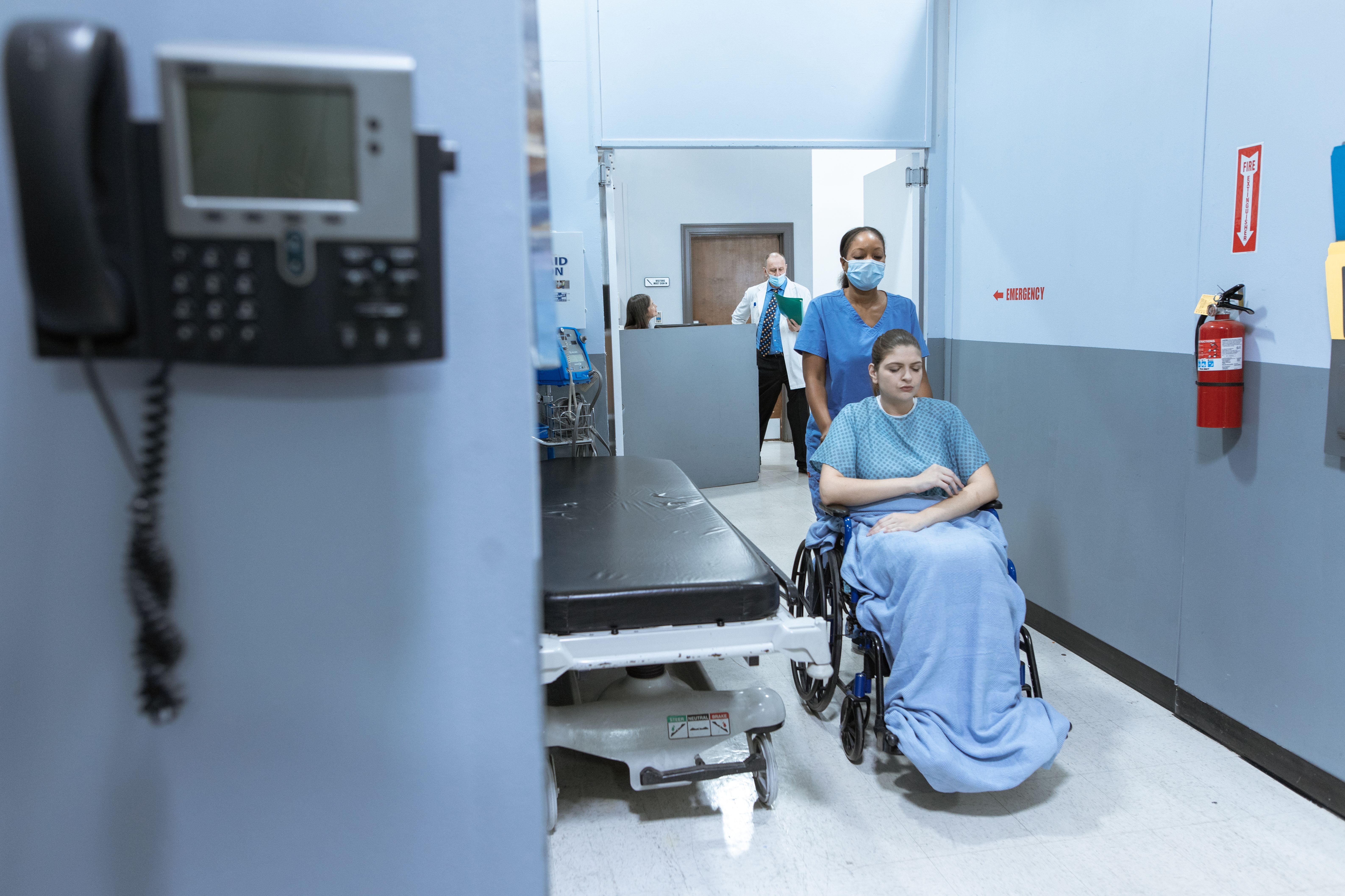 Nurse assisting a patient through a hospital corridor
