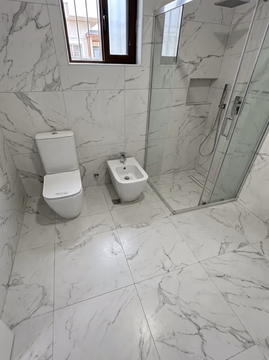 Banjo banjo me banjo bidet me dush me derë xhami dhe pllaka mermeri mbi të gjitha sipërfaqet e banjos.