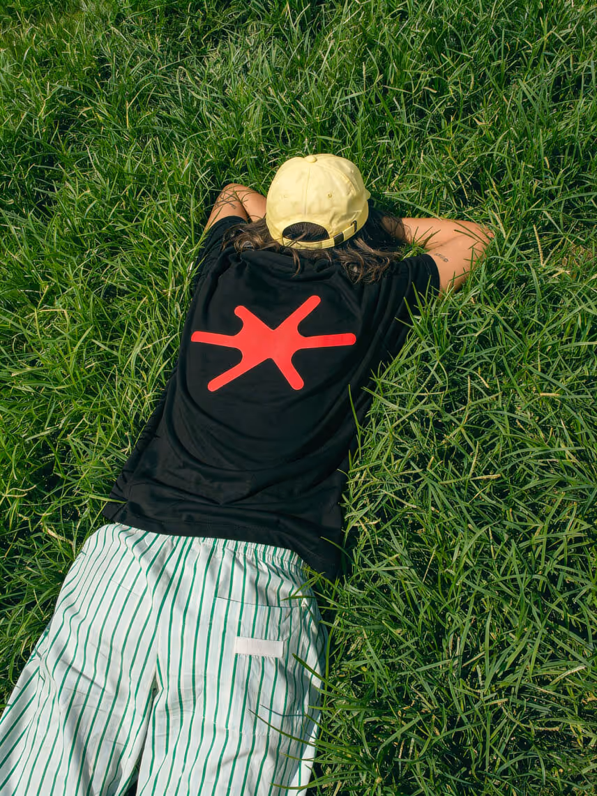 Group of five people engaged in a meeting at a large table in a bright modern office space with a neon 'BAR' sign in the background.