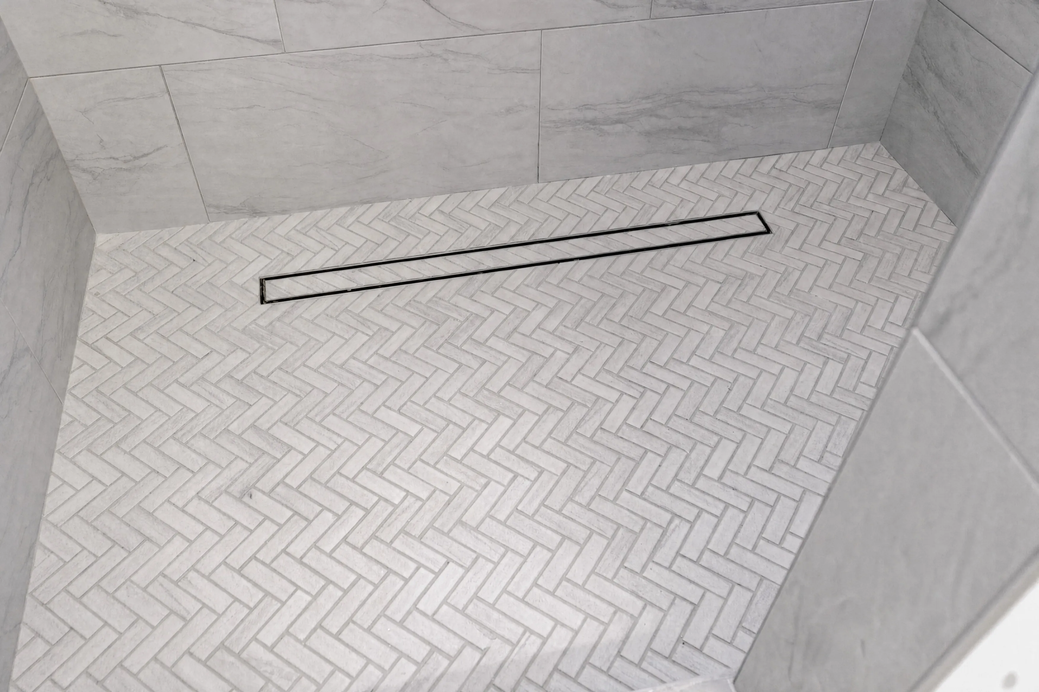 Herringbone marble floor tile with a linear drain