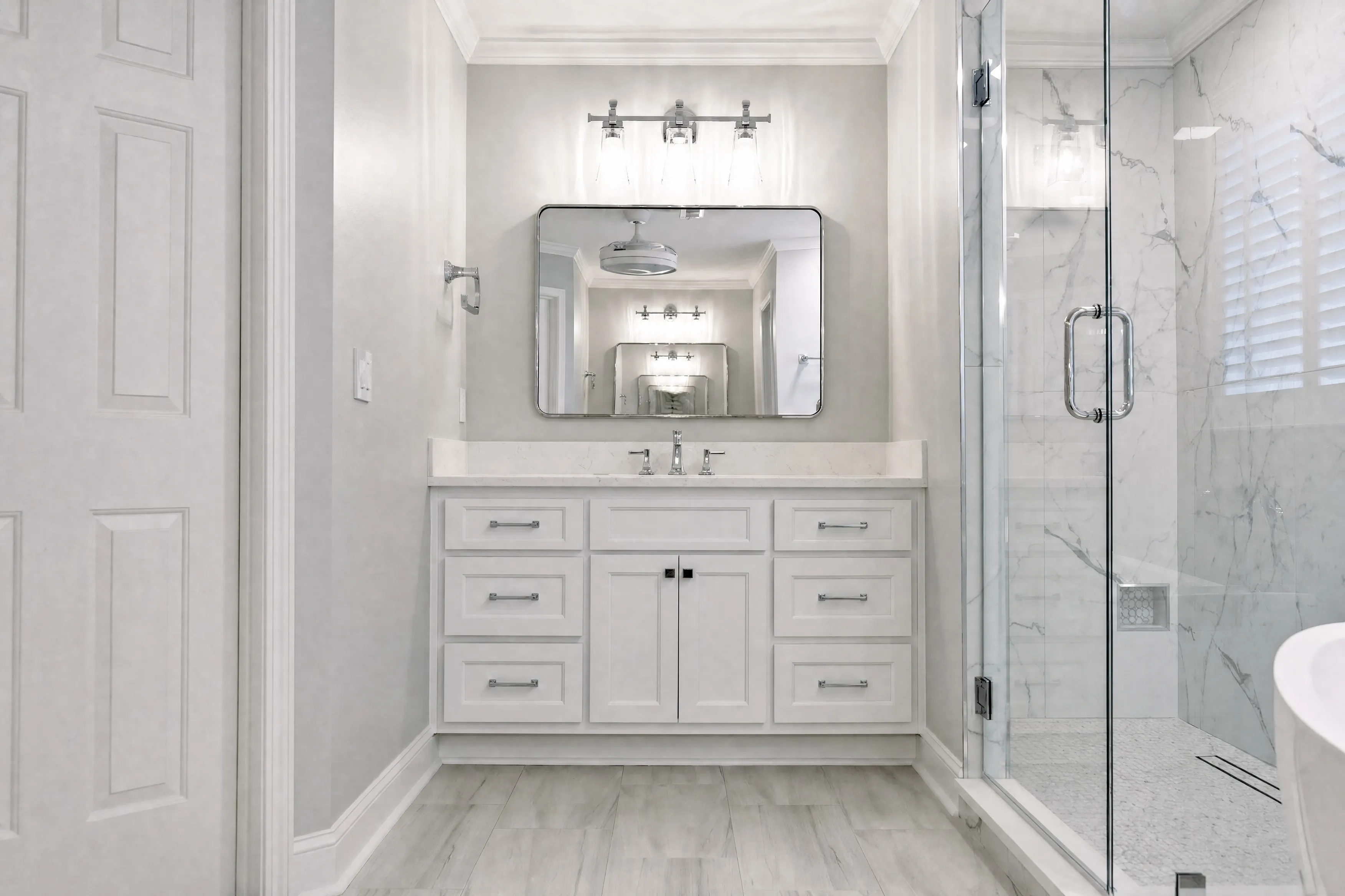 Custom vanity with framed mirror and wall sconces in a suite bathroom