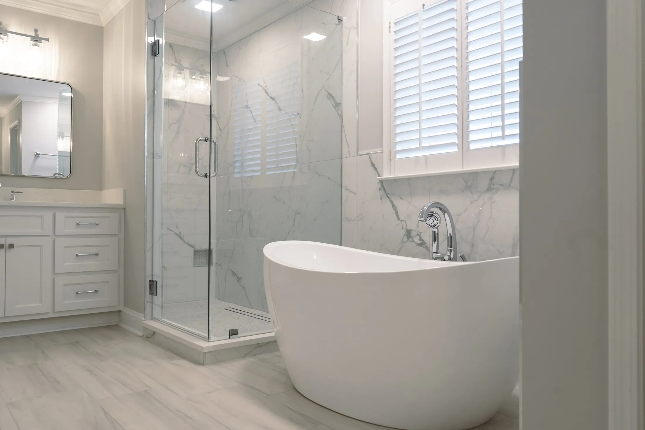 Marble-look master bathroom with a freestanding tub and glass shower