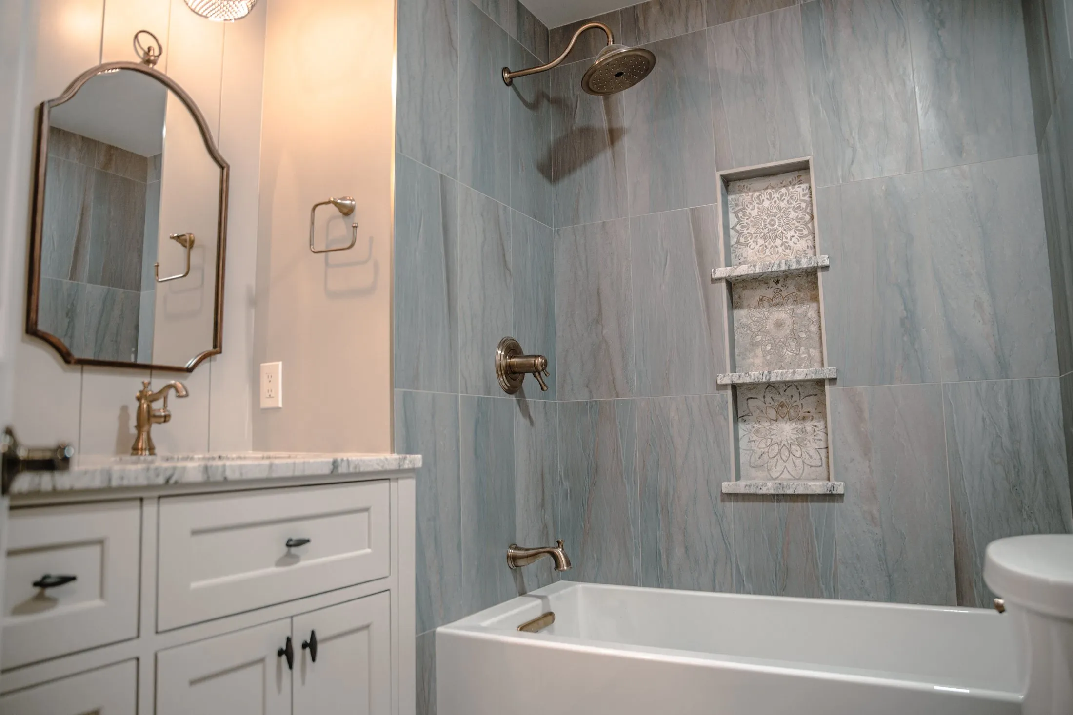 Guest bathroom with a stone-look tub surround and brass fixtures