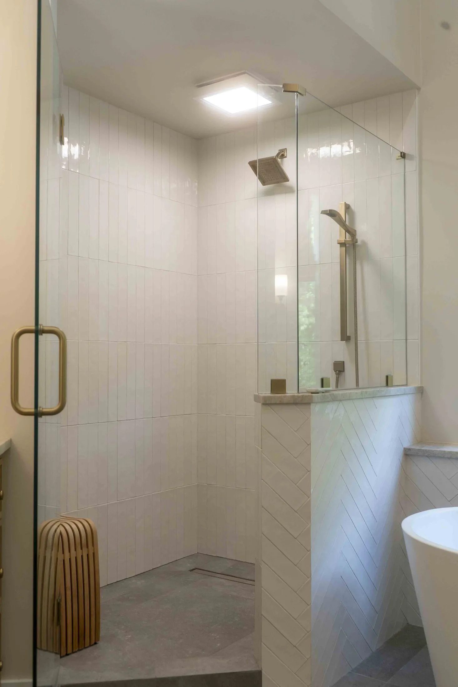 Walk-in shower and freestanding tub behind frameless glass