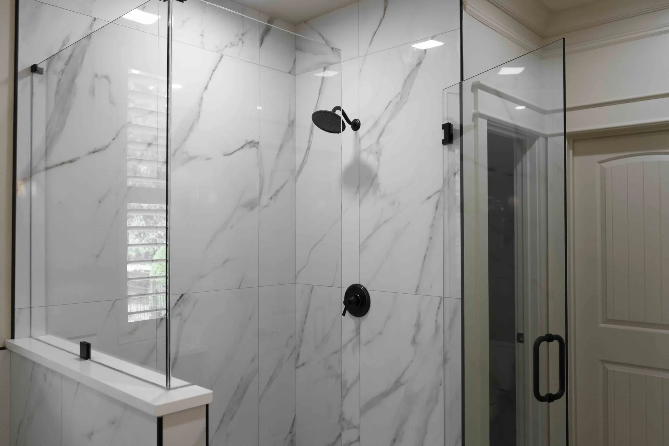 Frameless glass shower with a marble-look surround