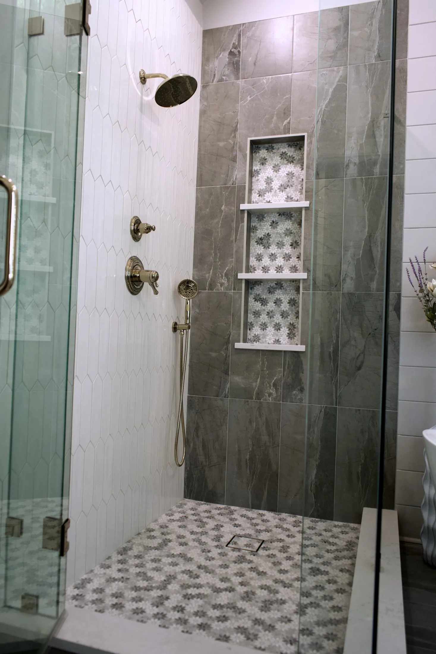 Walk-in shower with a patterned mosaic floor and tiled niche