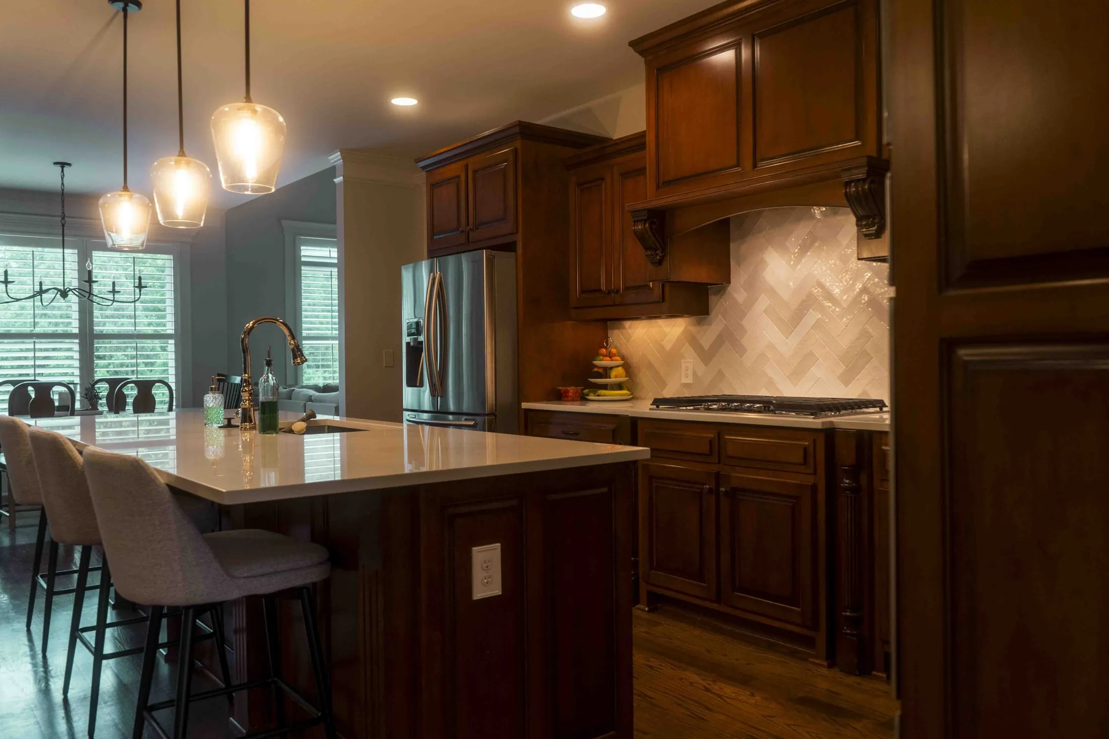 Kitchen with a herringbone tile backsplash, island and pendant lighting