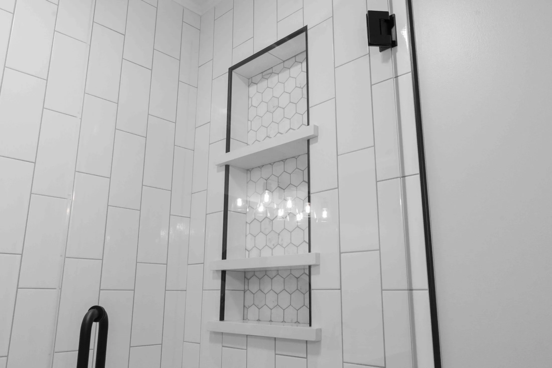 Shower niche with hexagon mosaic set into a subway tile wall