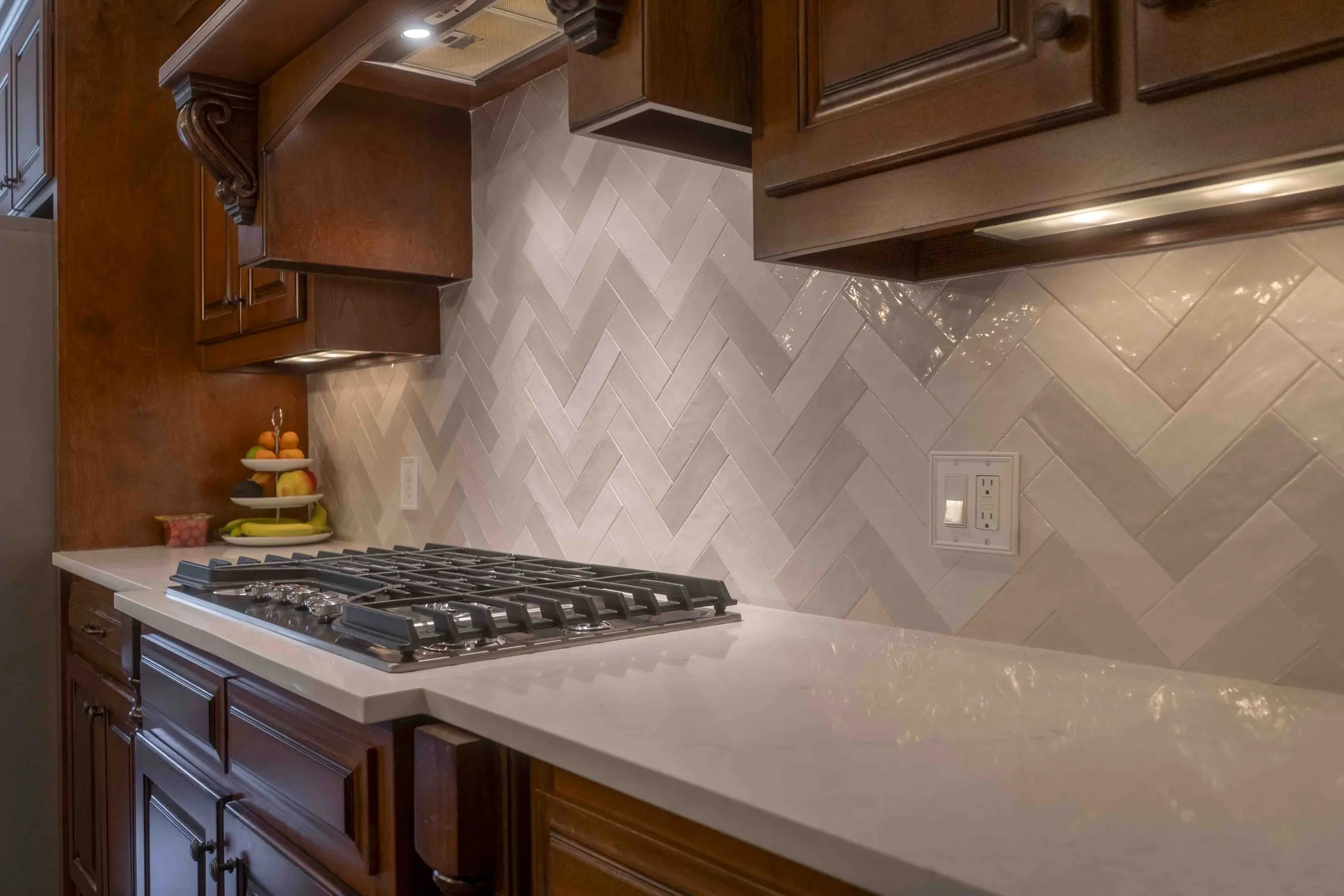 Herringbone tile backsplash above a gas cooktop