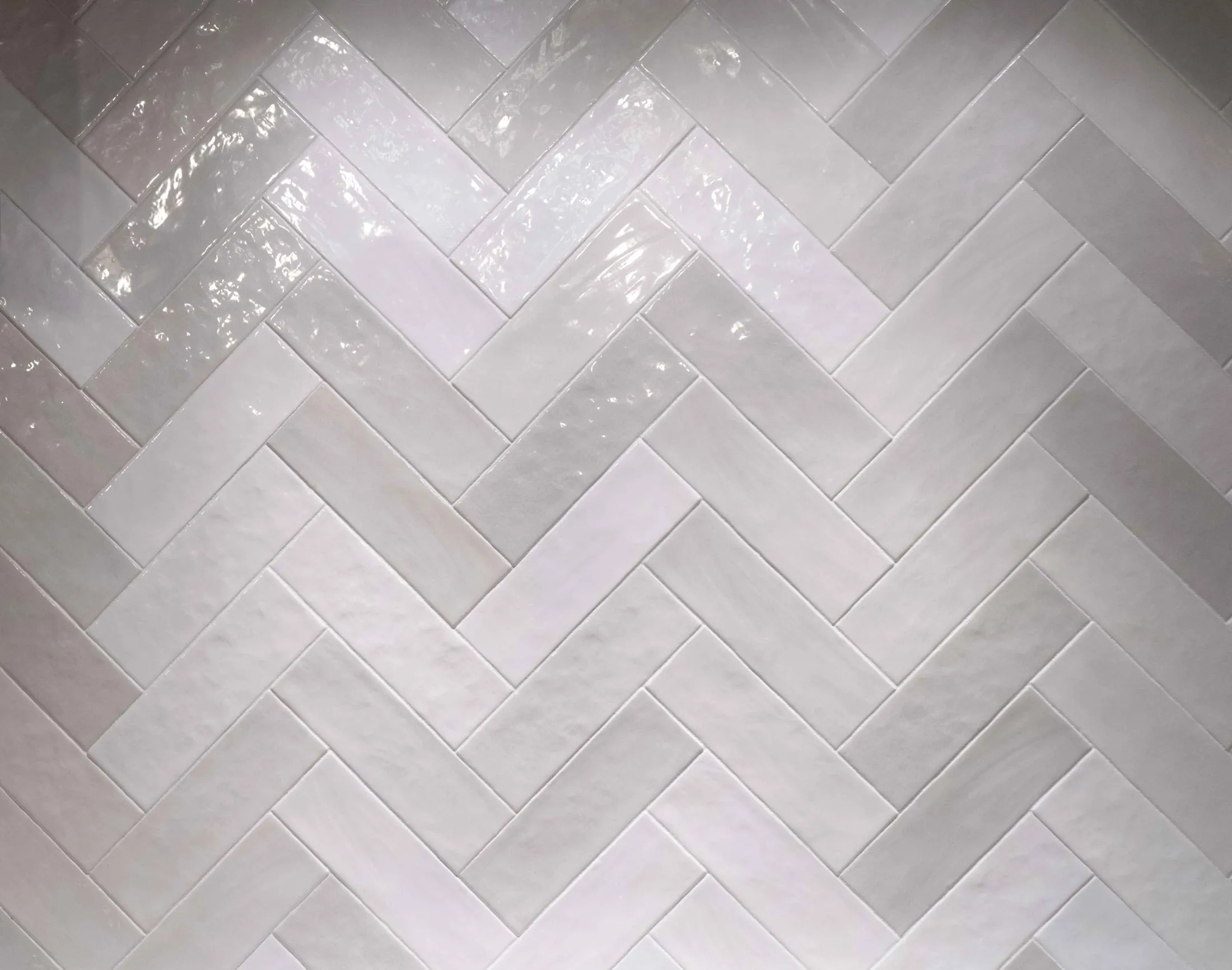 Close detail of a hand-set herringbone tile backsplash