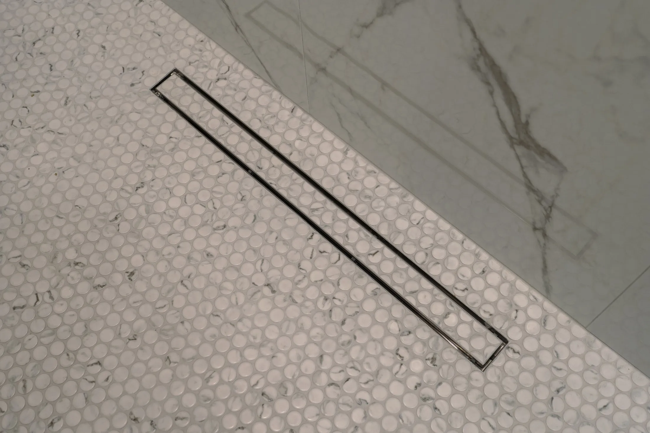 Penny-round mosaic shower floor with a linear drain