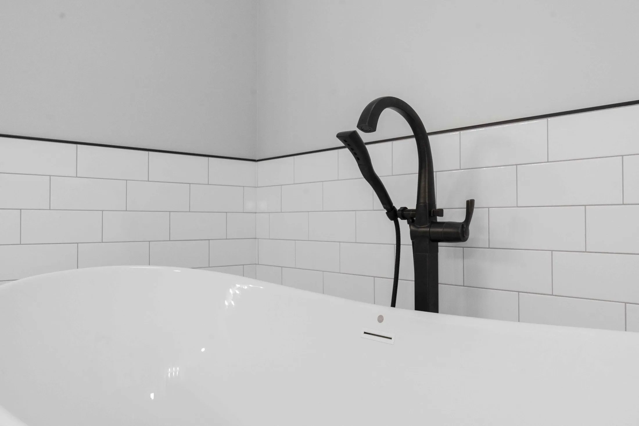 Freestanding tub and matte black tub filler against subway tile