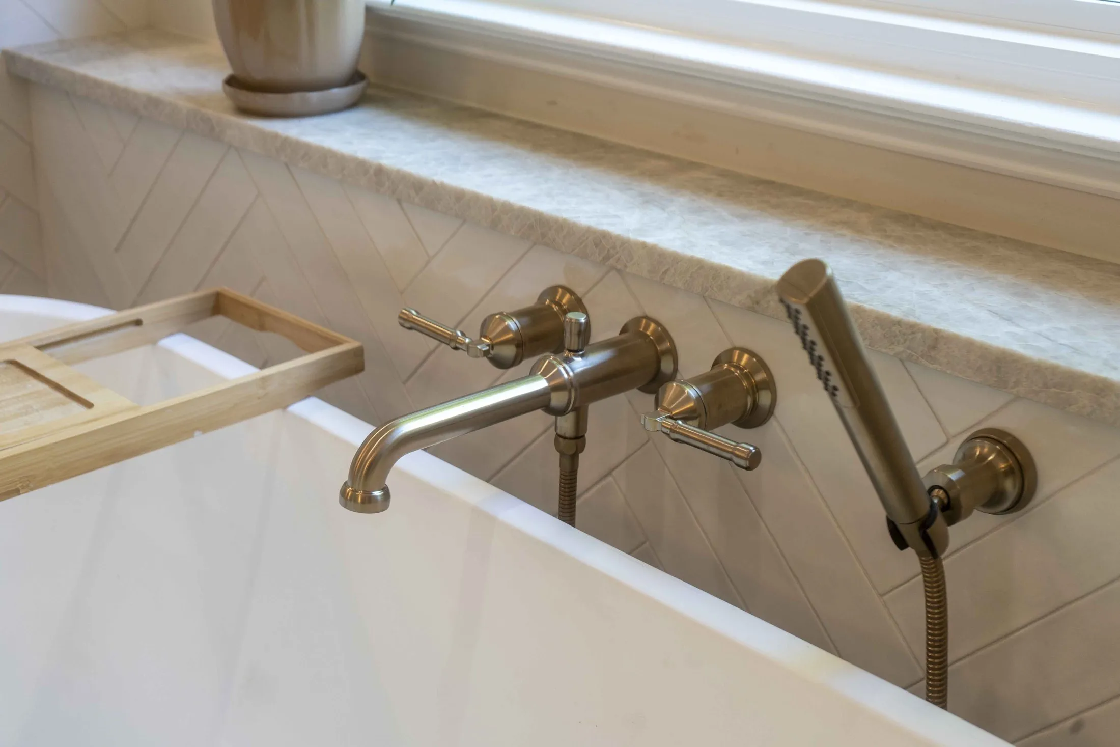 Brass wall-mounted tub filler above a marble ledge