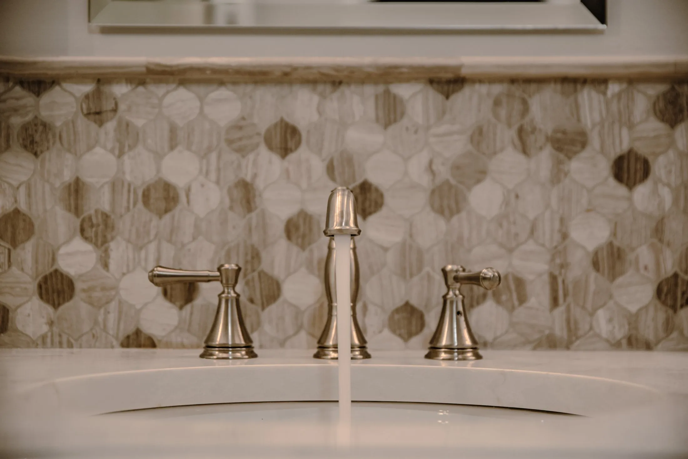 Brass faucet against a hexagon mosaic backsplash