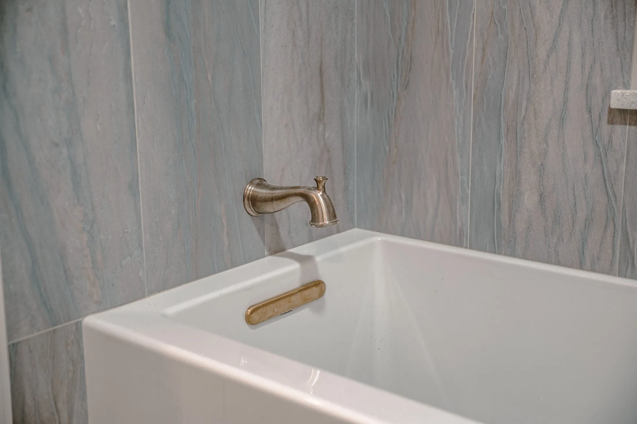 Brass tub filler on a stone-look tub surround