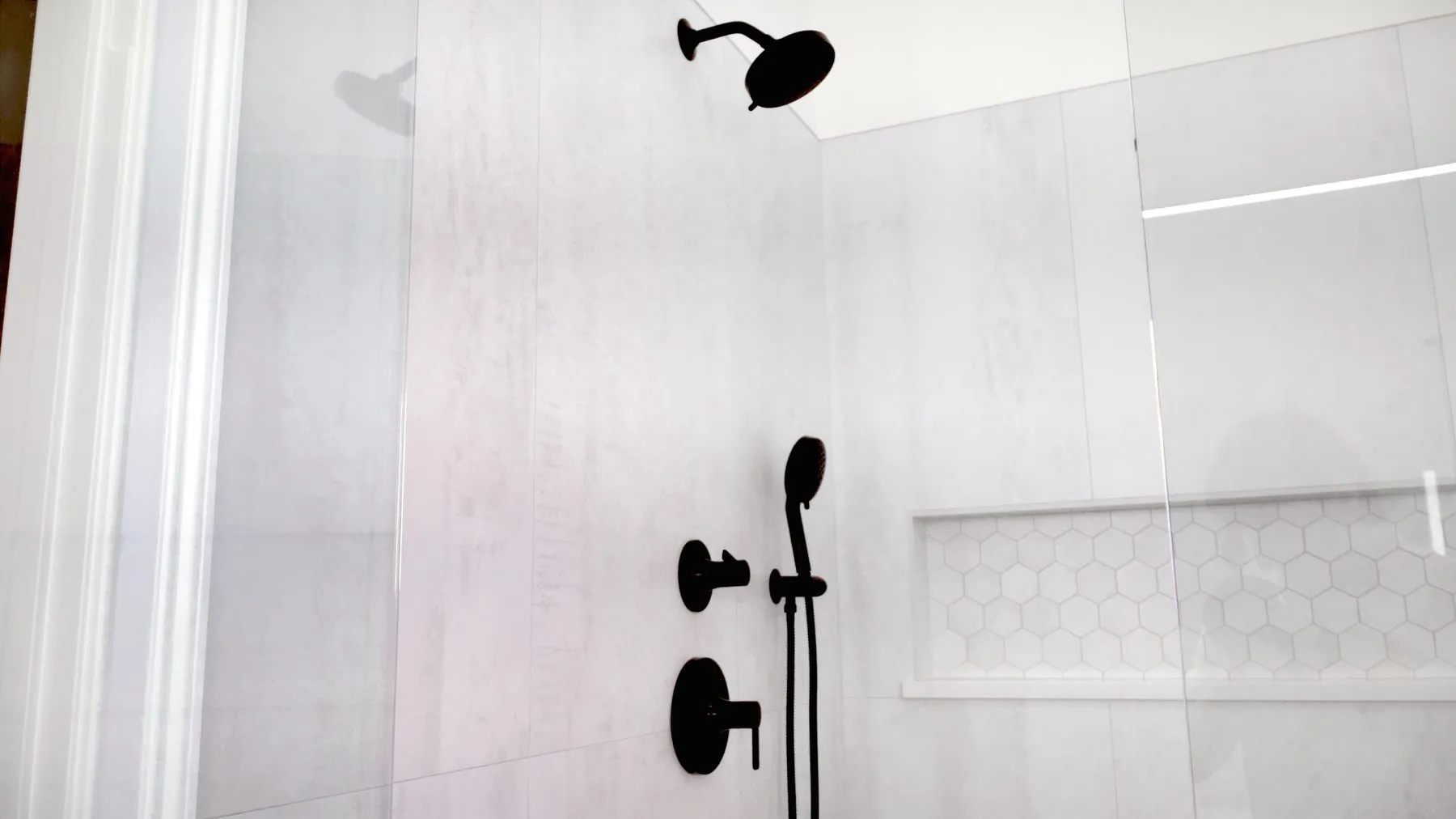 Walk-in shower with a rainfall head, matte black fixtures and large-format porcelain walls