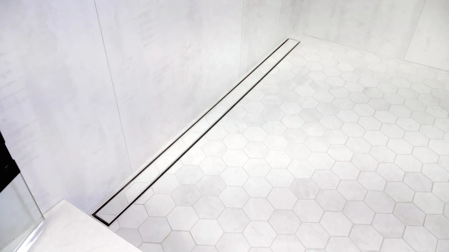 Linear drain set flush into a hexagon mosaic shower floor
